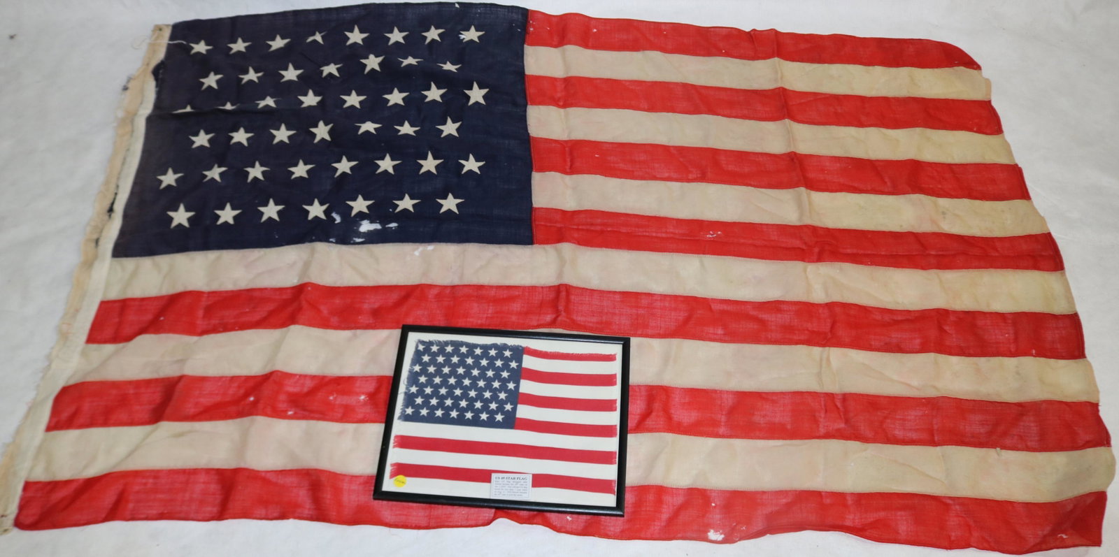 TWO UNITED STATES FLAGS. TO INCLUDE: A 45-STAR: FLAG (42" X 67") AND A RARE MINIATURE 49-STAR FLAG (9 1/4" X 13"). THE 49-STAR FLAG WAS DESIGNED AFTER ALASKA BECAME A STATE. IT LASTED LESS THAN ONE YEAR. IN 1959, HAWAII BECAME THE 50TH STATE. THE 4