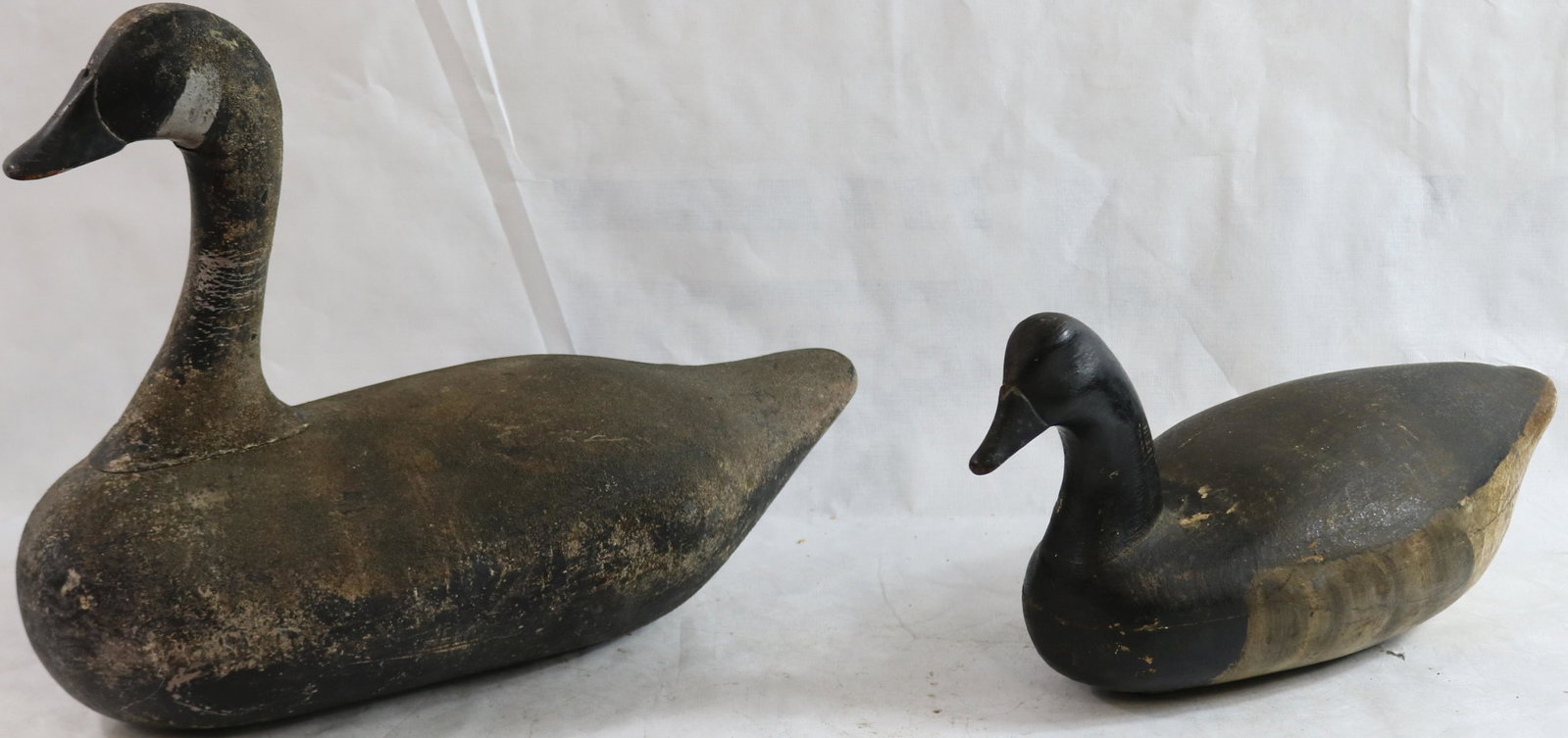 TWO WOODEN DECOYS TO INCLUDE A BRANT BY CHARLES: WILBUR, NEW JERSEY, CIRCA 1930, SHOWS AGE CRACKS AND TOUCHED UP PAINT. 9" HIGH, 19" LONG, 7" WIDE. ALONG WITH A CANADA GOOSE FROM NORTHERN VIRGINIA OR SOUTHERN NEW JERSEY, FLOCKED PAINT, CRACKED NECK,