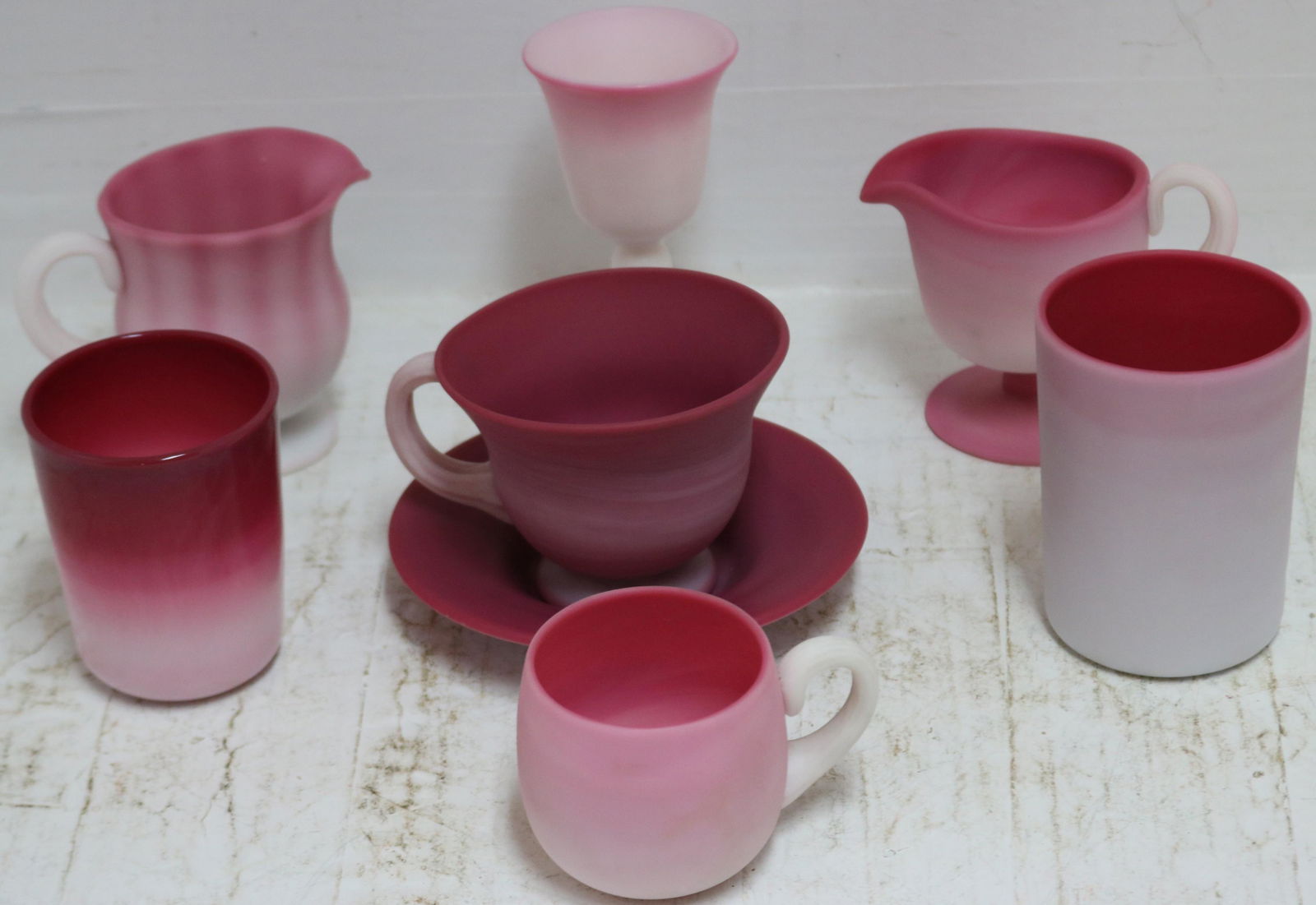 8 PIECES OF PEACHBLOW, POSSIBLY MT. WASHINGTON: AND PAIRPOINT, TO INCLUDE 4" TUMBLER, 3 1/2" TUMBLER, TWO 3 1/2" HANDLED CREAMERS, 2 1/2" PUNCH CUP, 4 3/4" WINE GLASS, RARE CUP AND SAUCER (CUP IS 3 1/4" HIGH, SAUCER HAS 5 1/2" DIAMETER). EXCELLENT