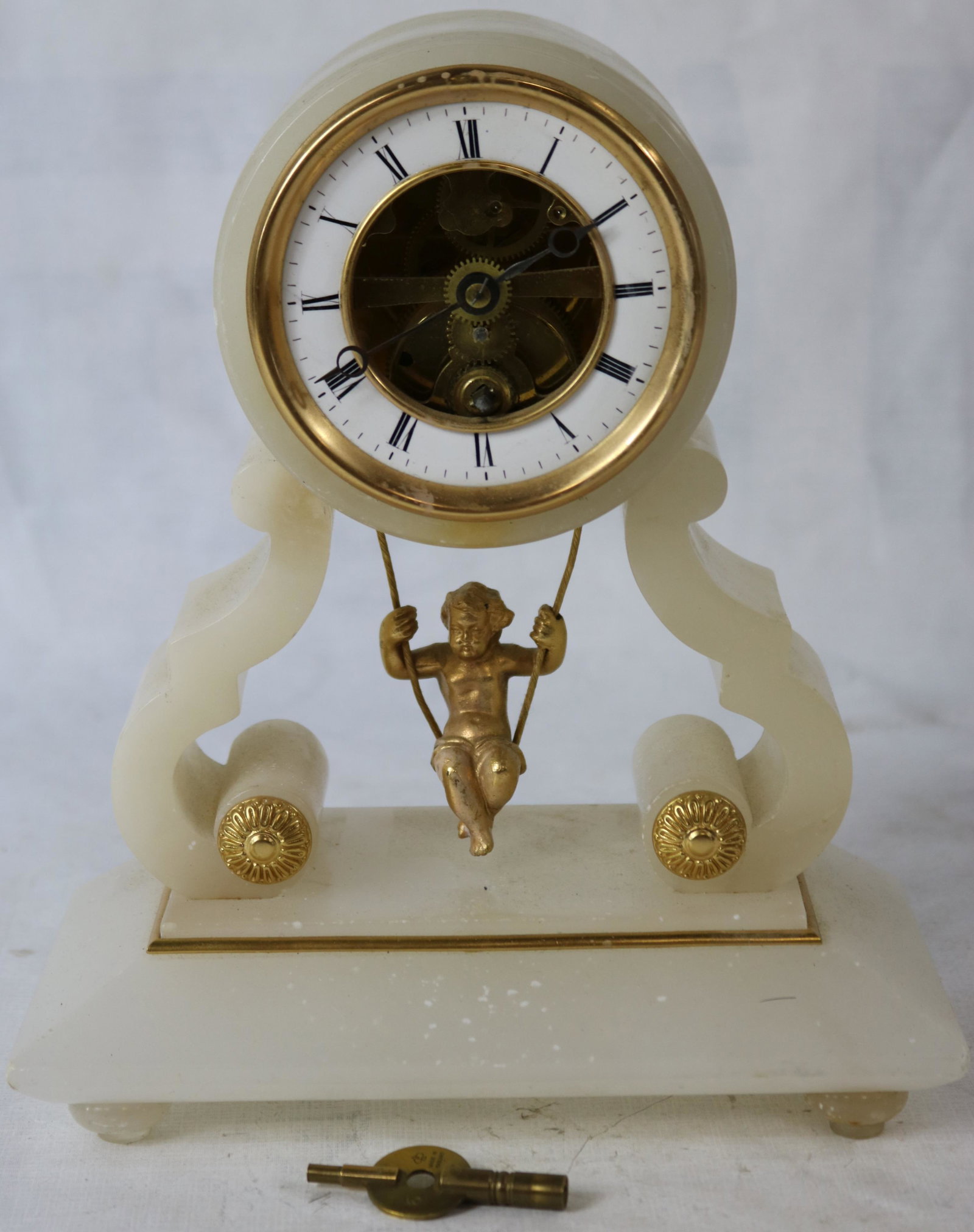 GILT BRONZE AND ALABASTER FRENCH CLOCK, MOVEMENT: MARKED BREVETE, WITH SWINGING CHERUB. CA. 1880. 9 1/4" HIGH, 8" WIDE, 4" DEEP. APPEARS TO BE WORKING, BUT NOT GUARANTEED. WITH ORIGINAL KEY.