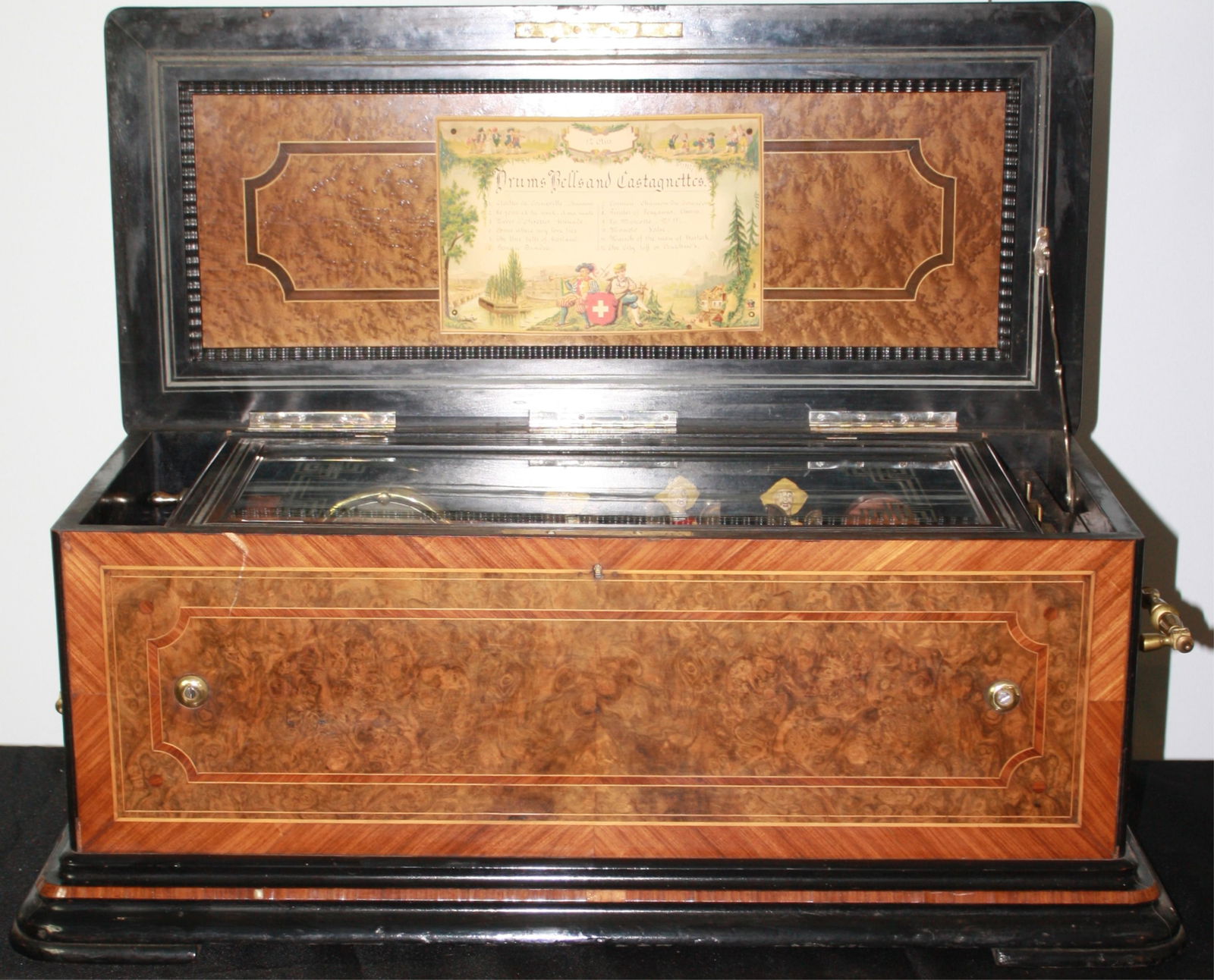 LATE 19TH CENTURY SWISS MANDARIN MUSIC BOX,: PROBABLY BY PAILLARD. 12 TUNES PLAYED ON BRASS CYLINDER, WITH ITS ORIGINAL LITHOGRAPH LABEL. THREE ASIAN CARICATURE AUTOMATON FIGURES PLAYING CASTINETTES, 2 DRUMS. ENGRAVED GLASS DOOR PANEL WHICH LIFT