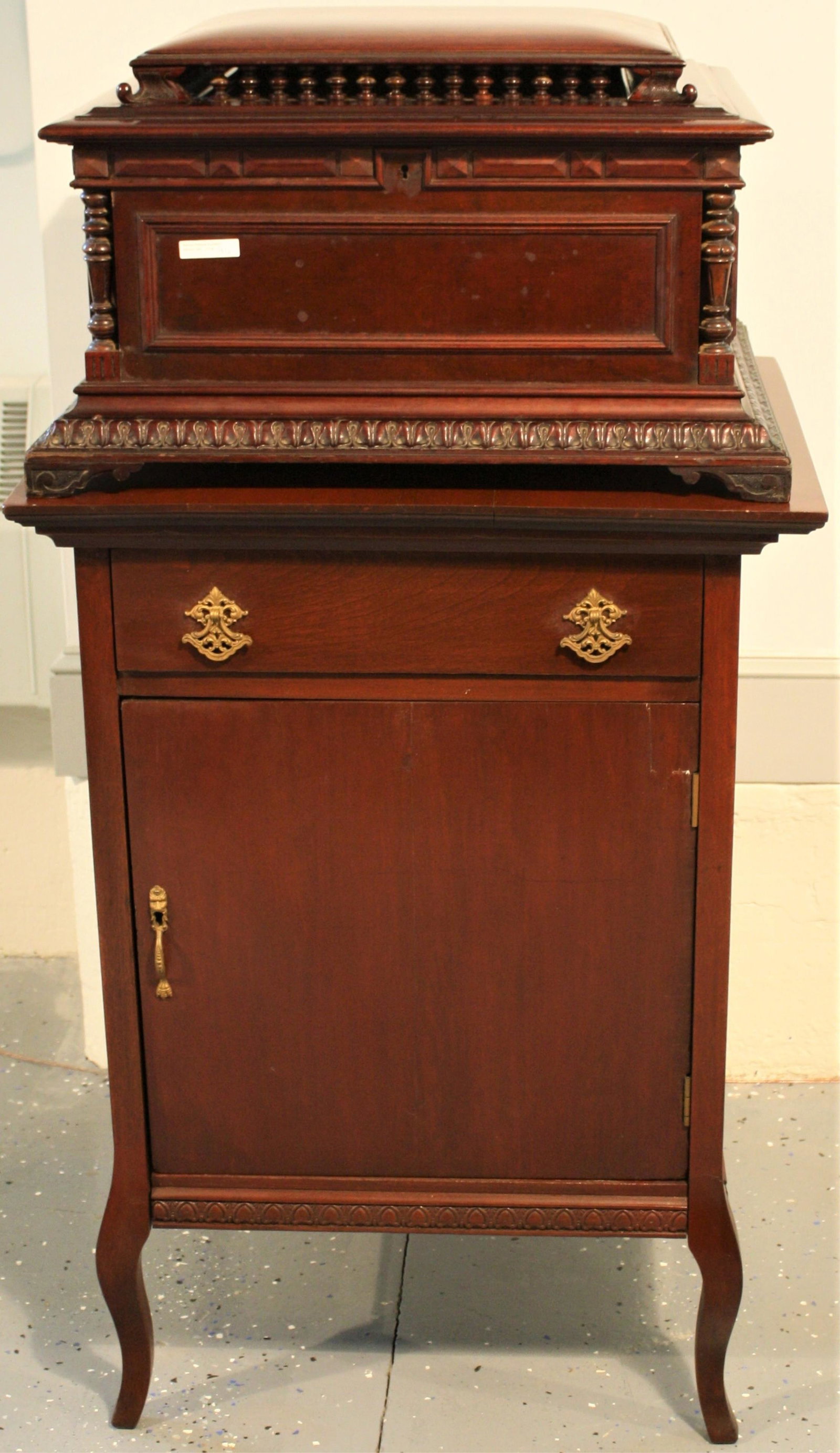 LATE 19TH C. REGINA MUSIC BOX, PATENTED 1896,: DOUBLE COMB. BOX HAS ITS ORIGINAL PAPER LITHOGRAPH LABEL DEPICTING PUTTI PLAYING INSTRUMENTS AROUND A HEROINE. THE BOX ITSELF IS MAHOGANY WITH ELABORATE FRETWORK GALLERY, CARVED GADROON BASE. ONE CORN