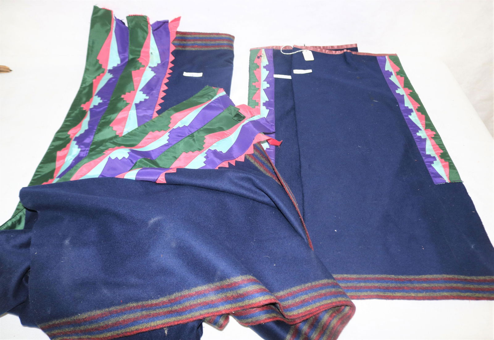 LOT OF THREE EARLY 20TH C CENTURY OKLAHOMA OSAGE: BLANKET AND LEGGINGS, RIBBON WORK DESIGN. WOOL FELTED TRADE CLOTH. FROM THE RED CORN FAMILY. NATIVE AMERICAN LEGGINGS ARE 27" LONG, 12 3/4" WIDE. BLANKET IS 54" X 89". SOME WEAR, MINOR MOTH DAMAGE. MU