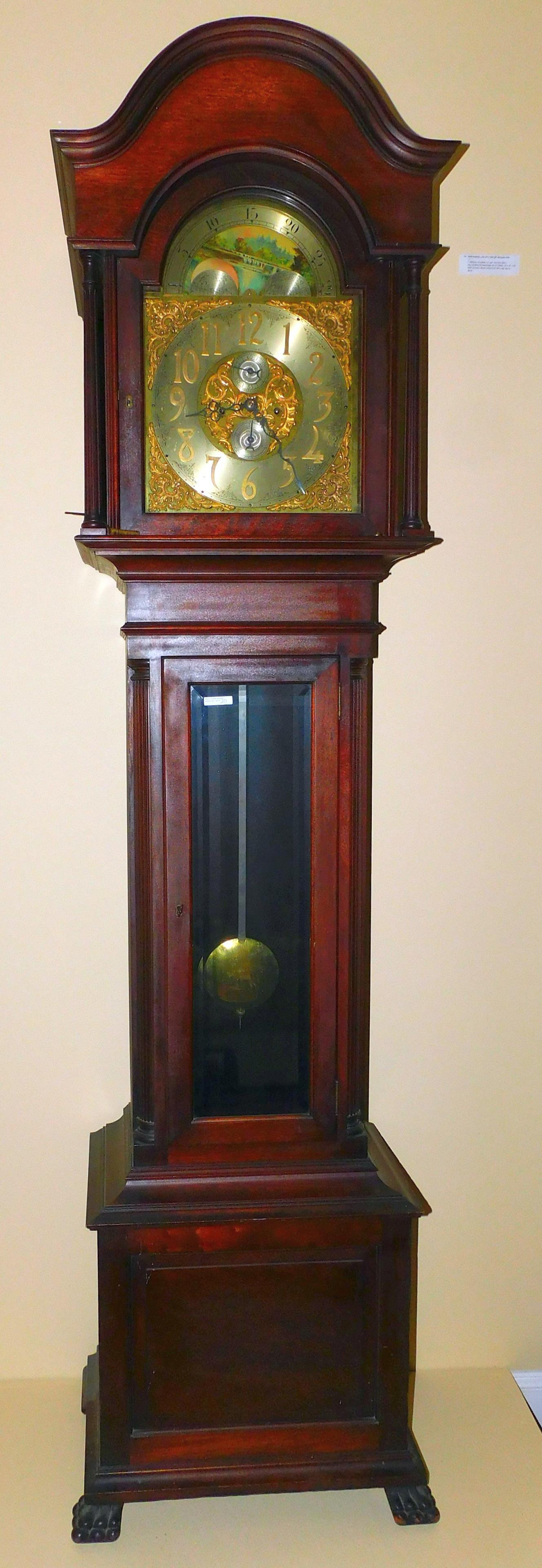 Early 20th century weight driven grandfather clock.: Sold by Smith Patterson Co., NY. Mahogany case, arched top, reeded column bonnet, brass moon phase dial, brass time and strike movement. Central case is flanked by reeded quarter columns with beveled 