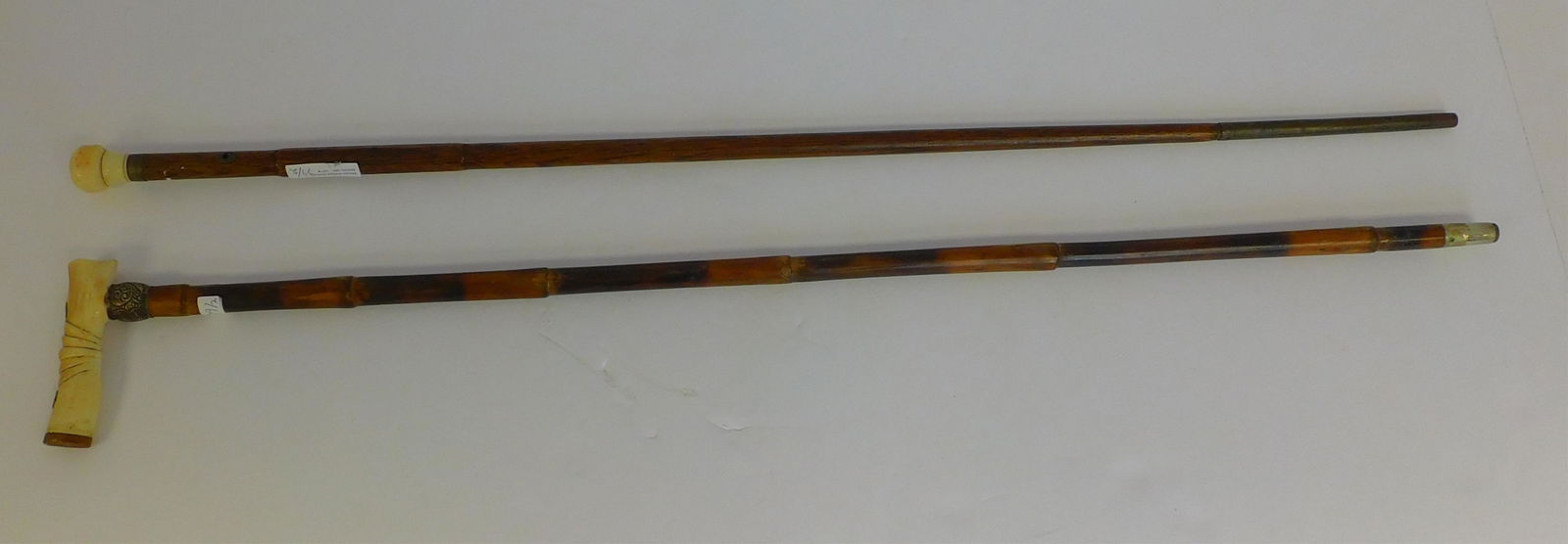 Two scrimshaw canes, late 19th century. One has a: sterling hilt and sterling mounts on top, bamboo shaft, 33 3/4" long. The other walking stick has a whale tooth top, and a dedication taken from the ship Lawrence. "H D Coyes" engraved on the top. Oak