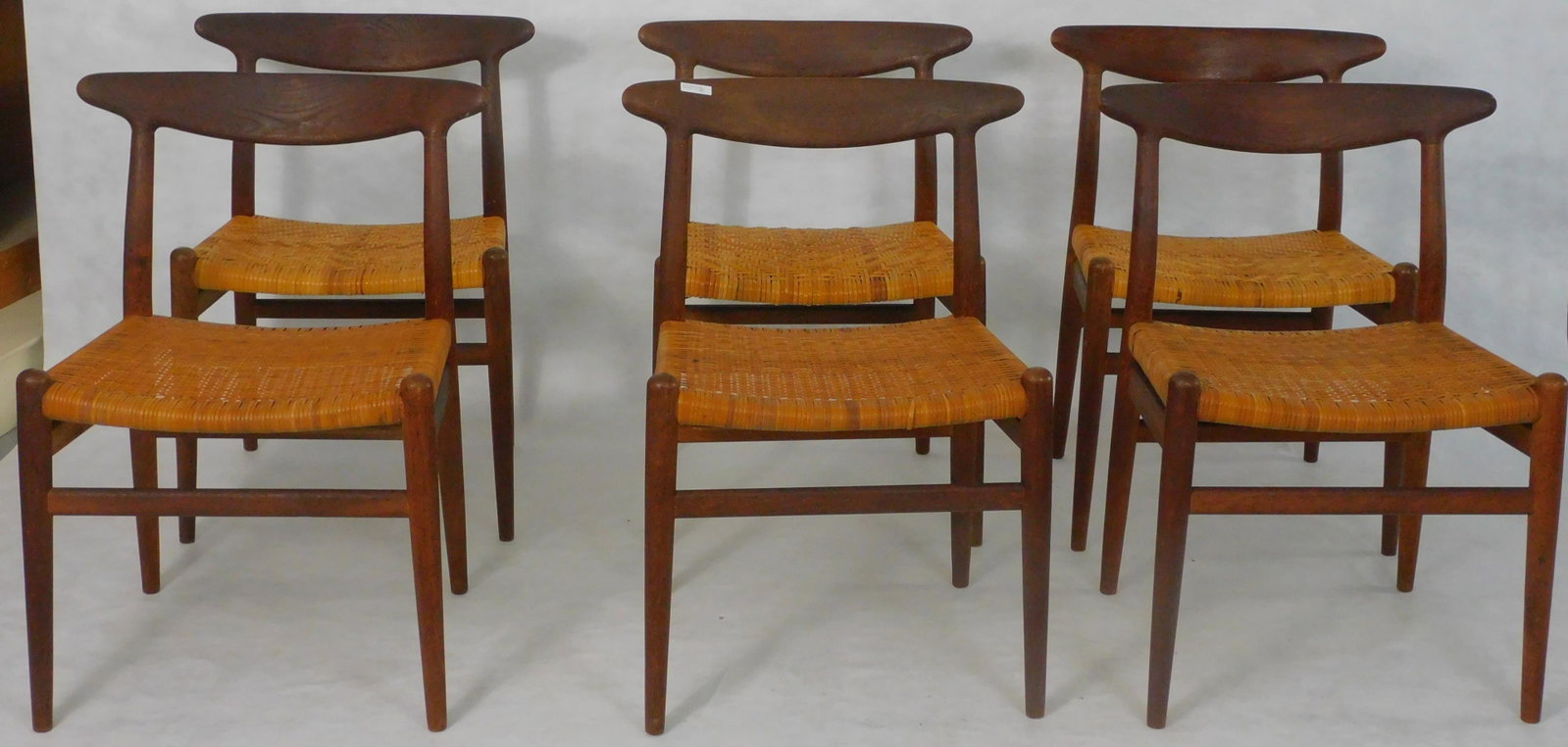 Set of six Hans J. Wegner (1914-2007) W2 dining: chairs for CM Madsen. Teakwood, woven cane seats. Stamped CM Madsen Fabriker, Made in Denmark. Ca. 1950s, mid century modern. Two different patterns in the caning of the seats. Very slight losses to s
