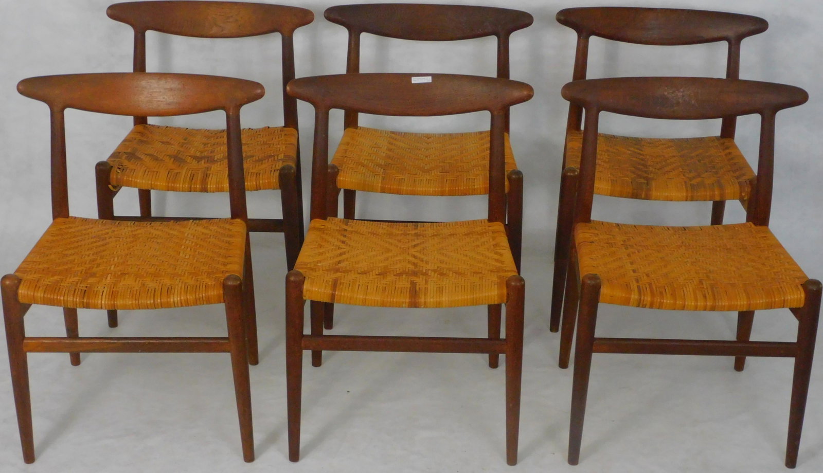Set of six Hans J. Wegner (1914-2007) W2 dining: chairs for CM Madsen. Teakwood, woven cane seats. Stamped CM Madsen Fabriker, Made in Denmark. Ca. 1950s, mid century modern. Three different patterns to the caning. Very slight losses to some of the 