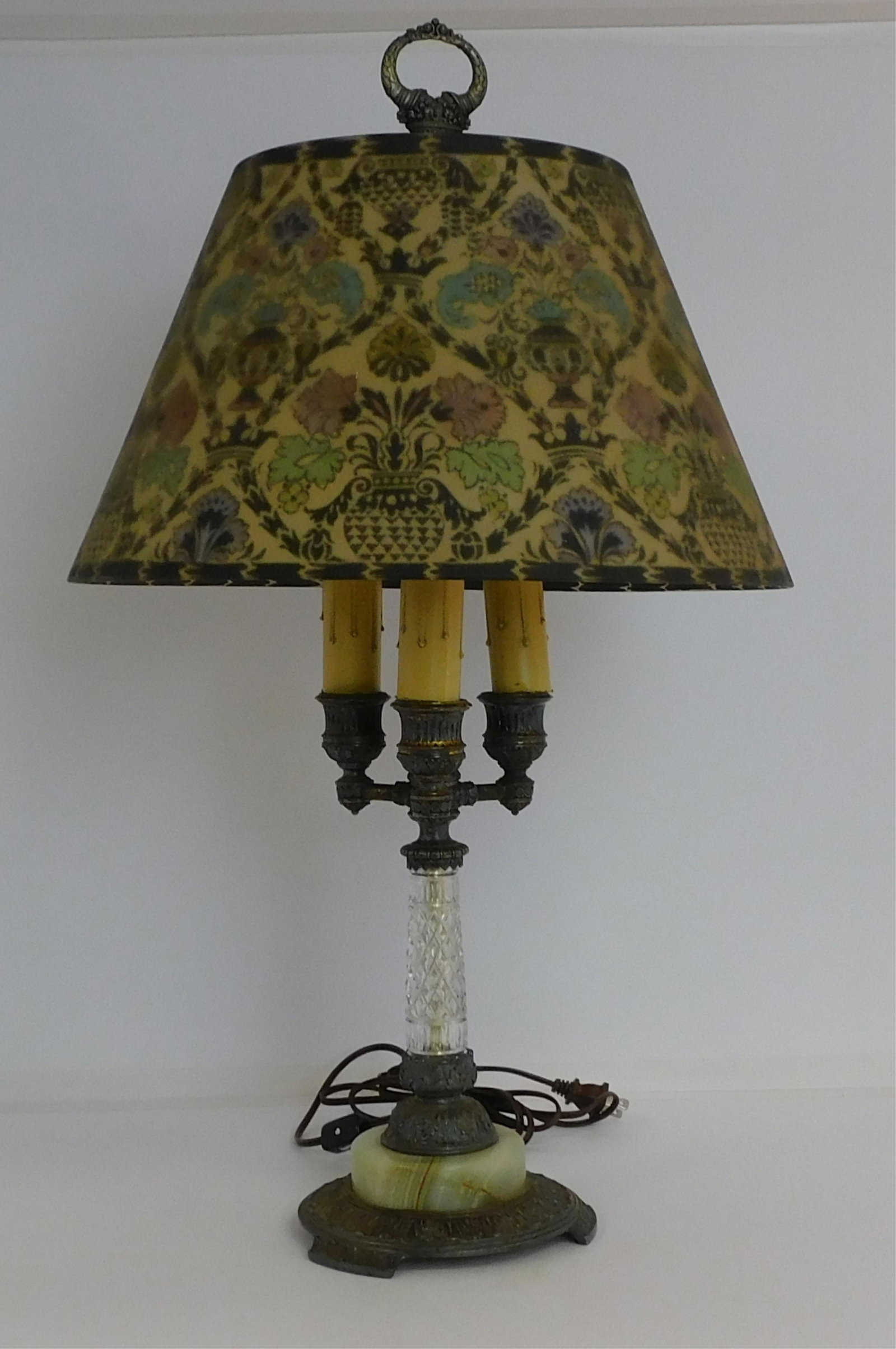 Early 20th century unsigned Pairpoint lamp, reverse: painted glass shade with geometric floral design. Directoire shape shade. Silver plated, cut glass, and onyx base. Three sockets. Lamp is 27" high. The shade is 9" high, 15 3/4" diameter. Overall good