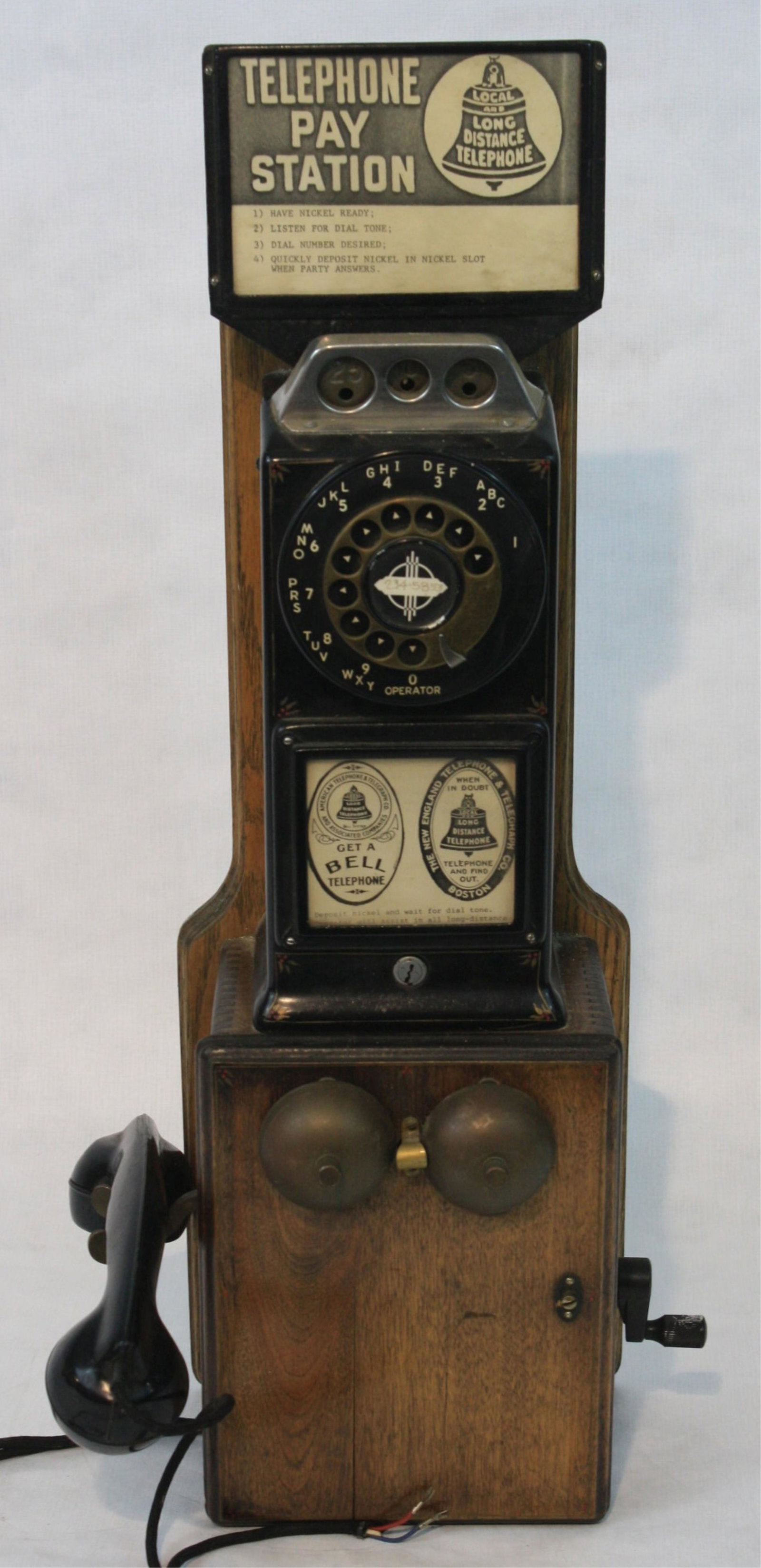 Vintage early 20th century wall hanging pay telephone.: Maple case, ca. 1920. Original paper placard 5, 10, 25 cent slots. Exterior bells on front. Side crank. Original receiver. 27 1/2" high, 9" wide, 9" deep. Good condition.