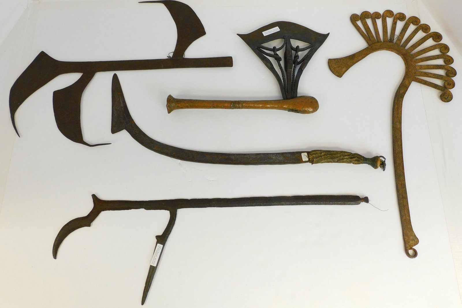 Five 20th century African weapons. To include: wrought: iron and copper wrapped throwing axe, 15" long, 9 3/4" wide. Wrought Azande iron throwing knife, 27" long, approx. 9" wide. Wrought iron knife with braided rope and wood handle, 26" long. Two wrought 
