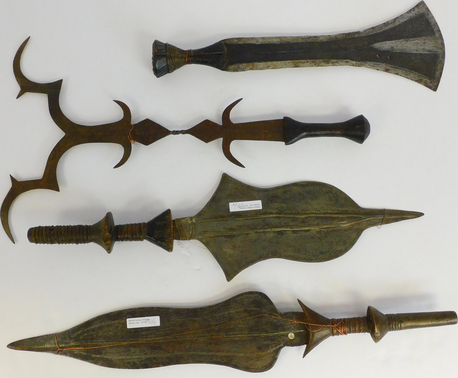 Four 20th century African weapons. To include: metal: throwing knife with wooden handle, Kuba people, 17" long. A metal throwing knife with a wooden handle, Kuba people, 20" long. Iron Azande sword, carved wooden handle, 21" long.