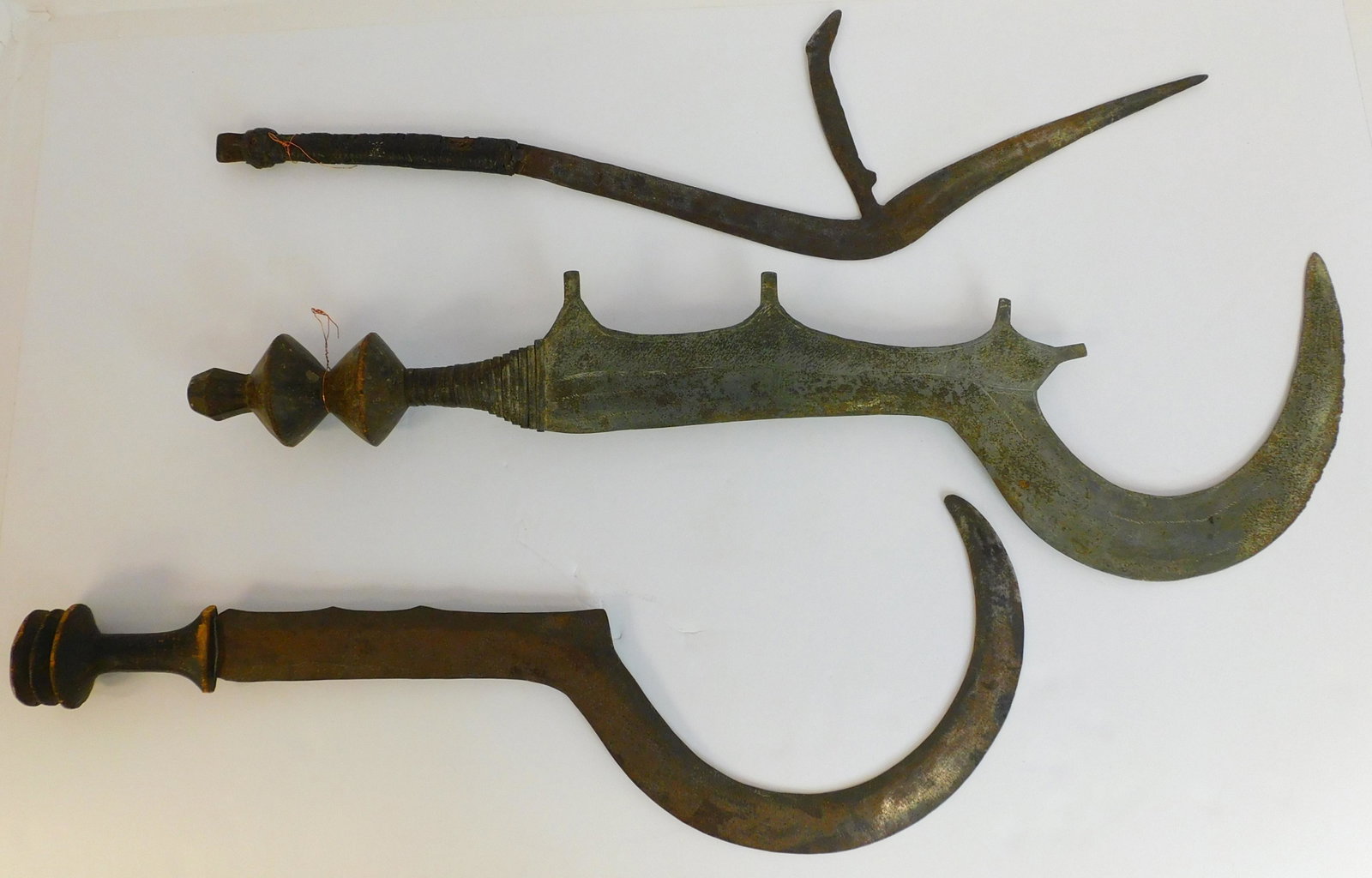 Three 20th century African weapons, Azande. To: include: wood and iron throwing axe, 25" long. Large sword, carved wooden handle, 30 1/2" long. An iron sword, 28" long with a woven leather handle.