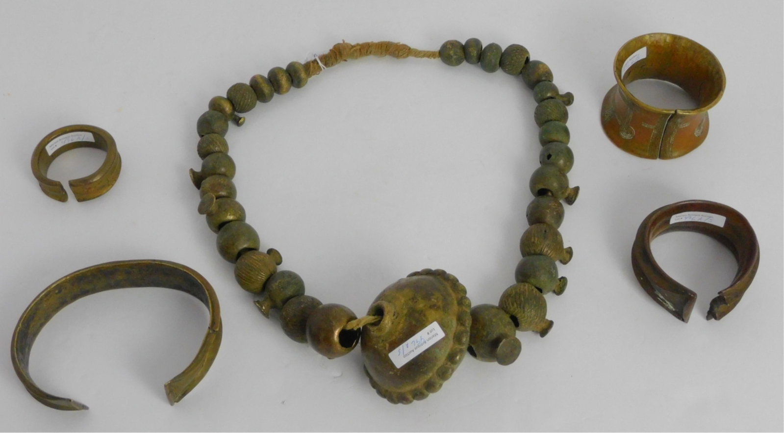 Lot of early African jewelry to include: neck: torque, Cameroon, brass, 6 1/2" x 4". A gilt bracelet, Cameroon, 3" x 2 1/2". Mid-19th century Portuguese copper, African-made bracelet, 3 1/2" x 2 3/4". A late 18th century Nupe Nigerian belt necklac