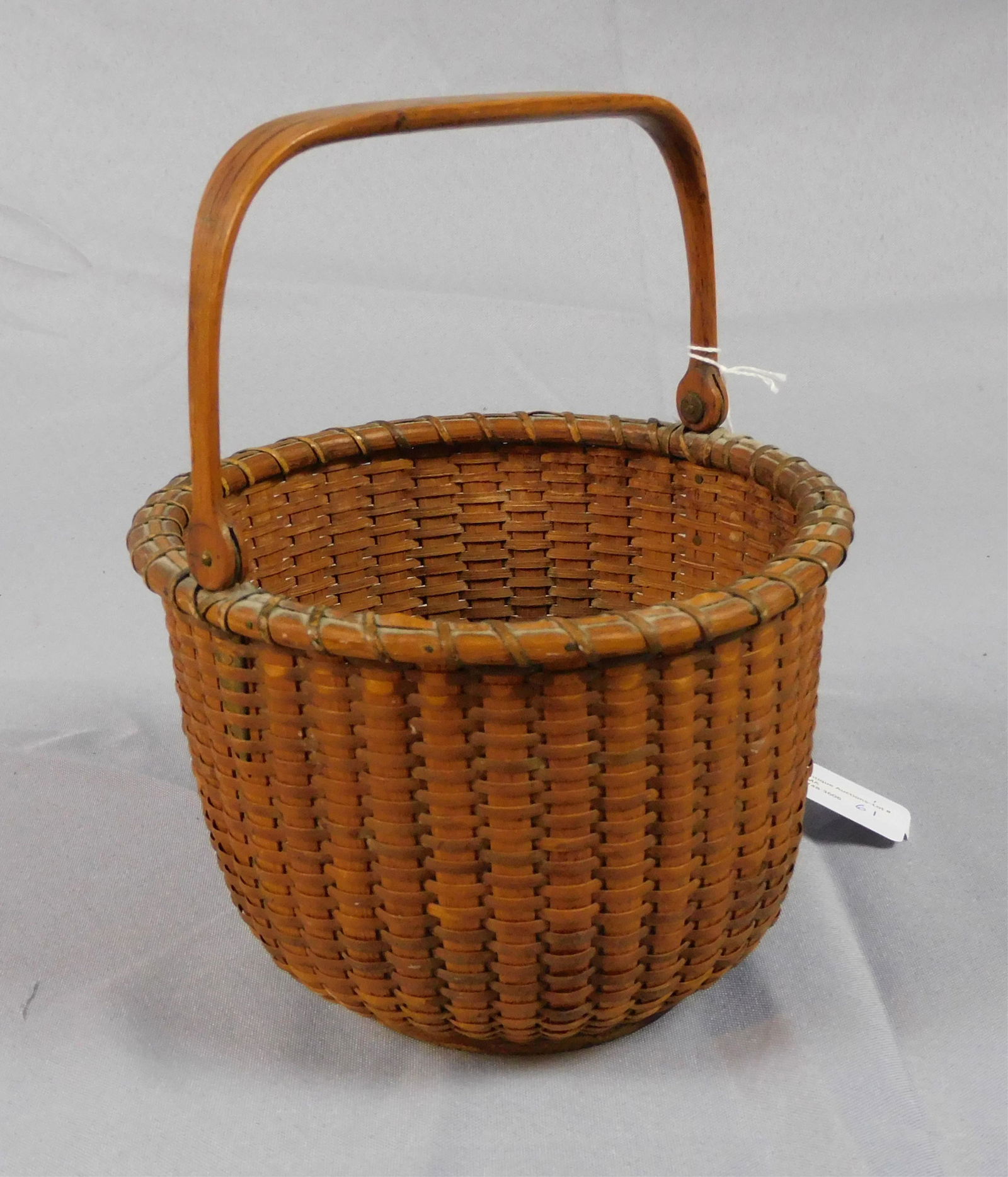 Nantucket lightship basket, mid-19th c. Swing: handle, remnants of old label on bottom. Rich old patina. 8 1/2" high with handle. 7" diameter. In fine original condition, nearly flawless.