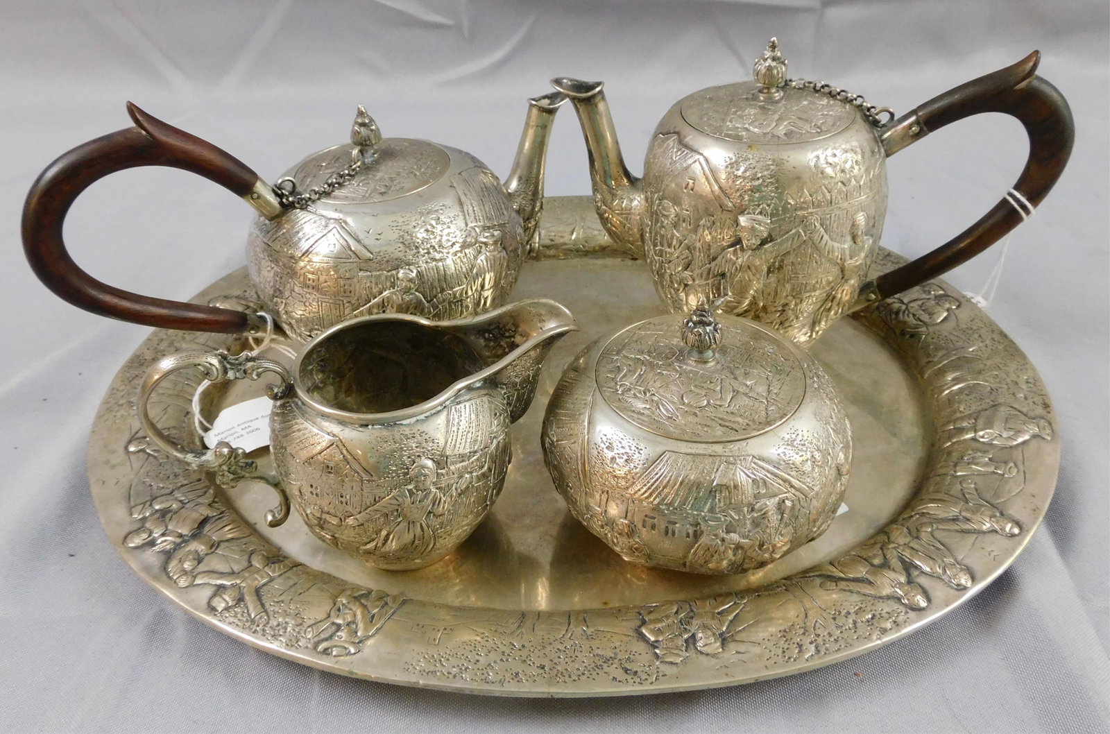 5-piece Continental silver tea and coffee: service, possibly Dutch. Ca. 19th c. Embossed with village scenes. Wooden handles. Includes: coffee pot (7 1/2" wide, 5 1/2" high), teapot (8 1/2" wide, 5" high), round covered sugar (4" diameter, 3 1