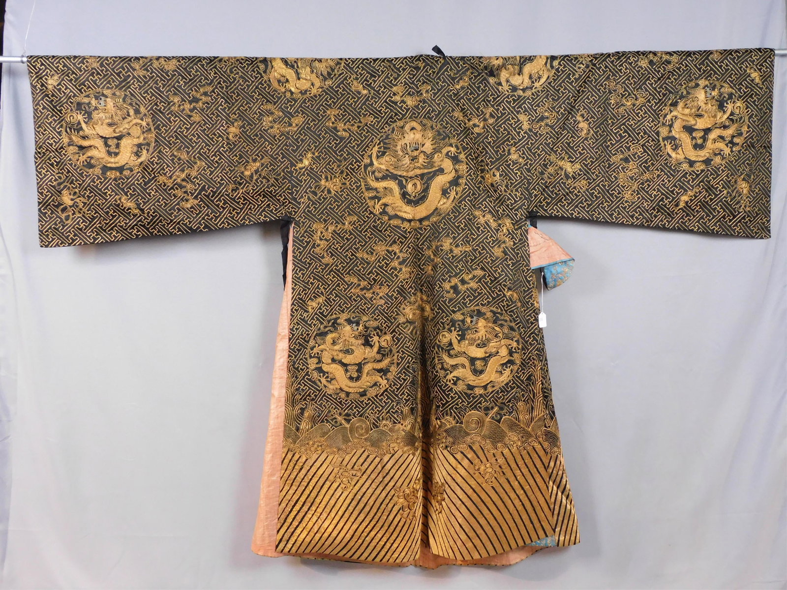 (2) Qing Dynasty garments, 19th c. To include:: overskirt with embroidery of dragons, central flower, waves, and clouds. Waistband comprised of a plain weave linen, under which is a printed cotton depicting flowers and stylized lions. Fair conditio