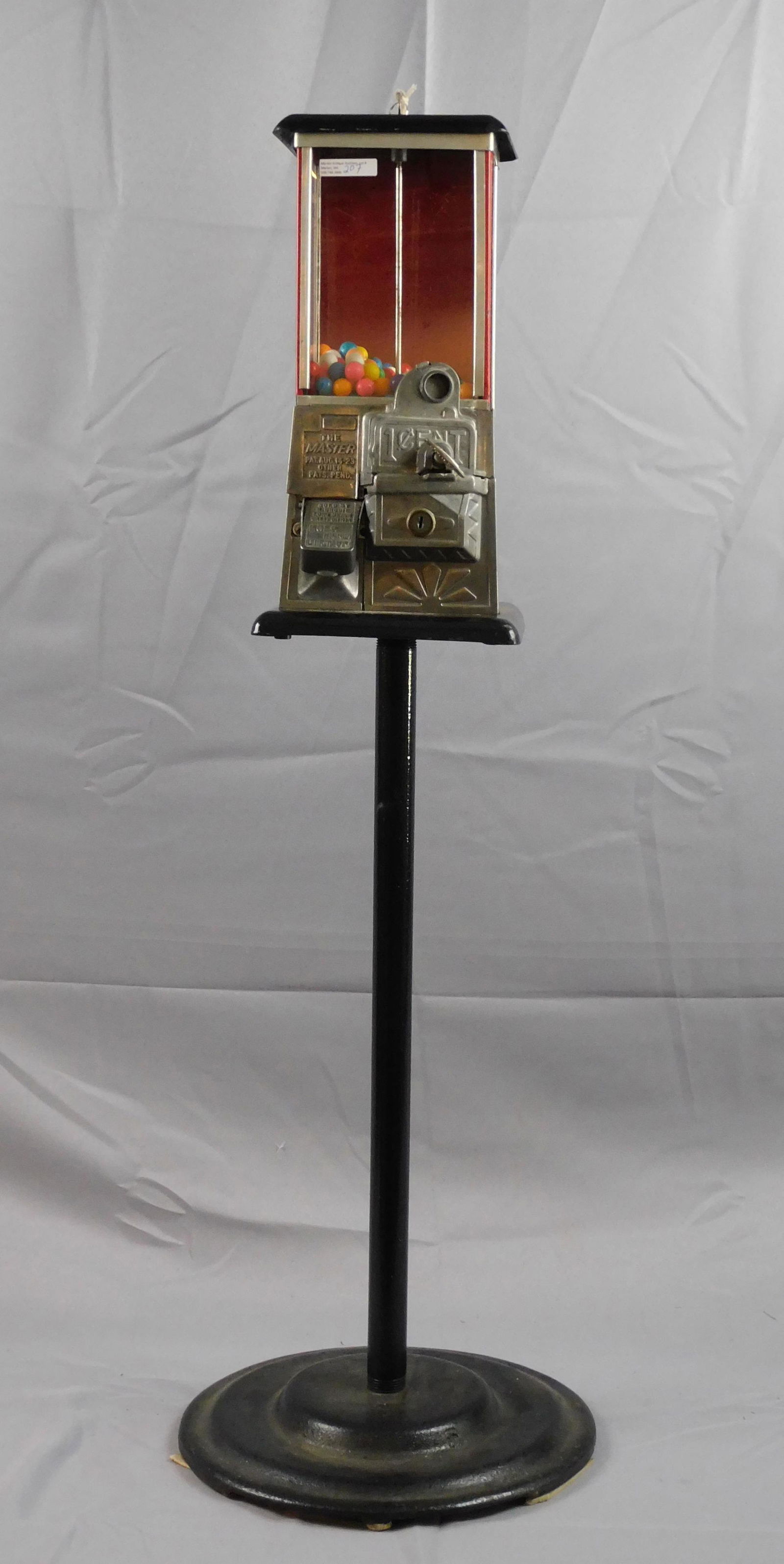 Norris Master gumball machine, standing. 1 cent.: Pat. Aug 14, 1923. Porcelain and metal, red and black painted. Comes with a key. 43 1/4" high, machine is 7" wide x 8" deep x 15" high, base is 14" diameter. Good overall condition, working.