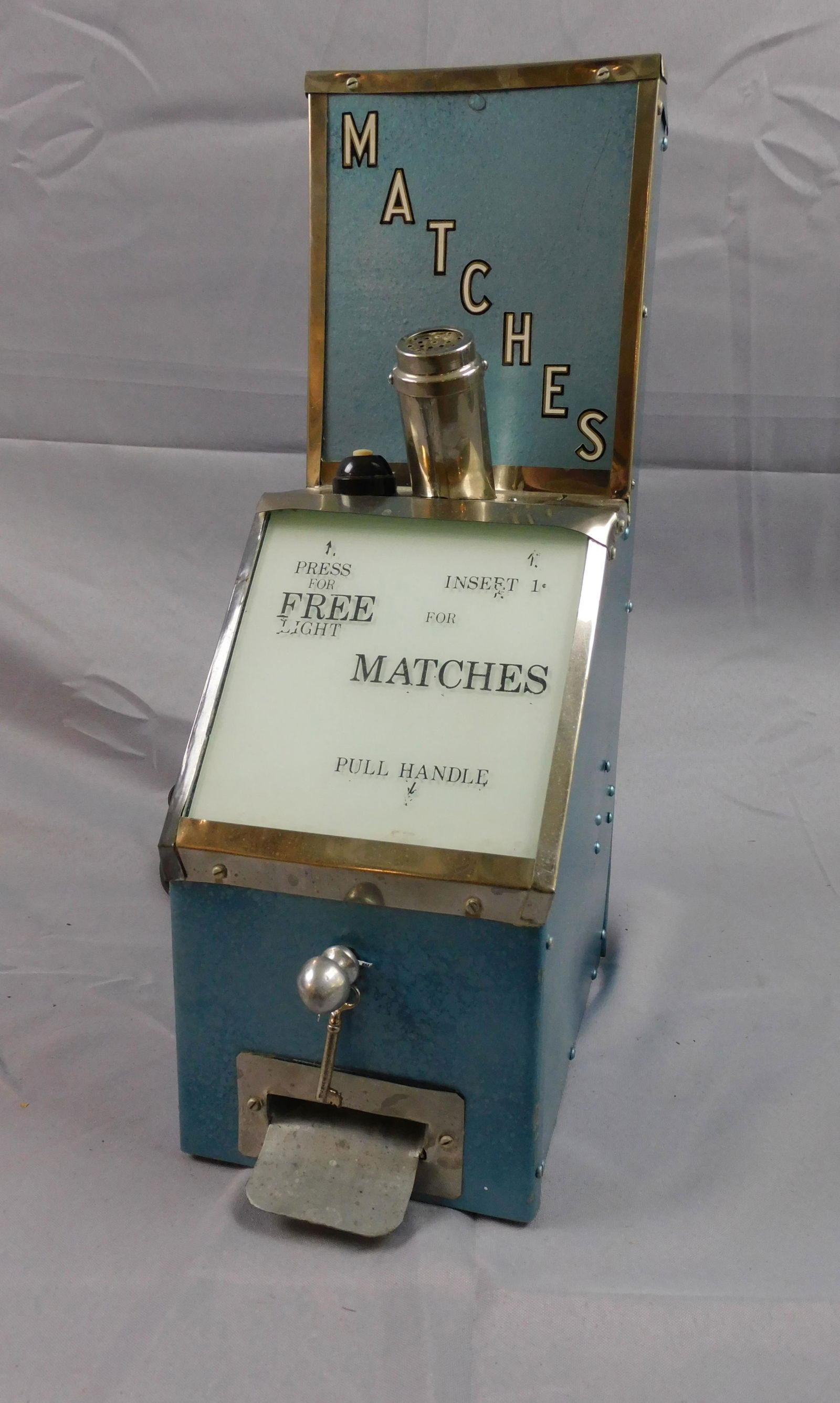 Coin operated matches vending machine with cigar: lighting device, ca. early 20th c. Metal with chrome trim, has the original key. 1 cent. Has an electric cigar lighting attachment. Working, overall good condition, slight areas of wear. 6 3/4" wide,
