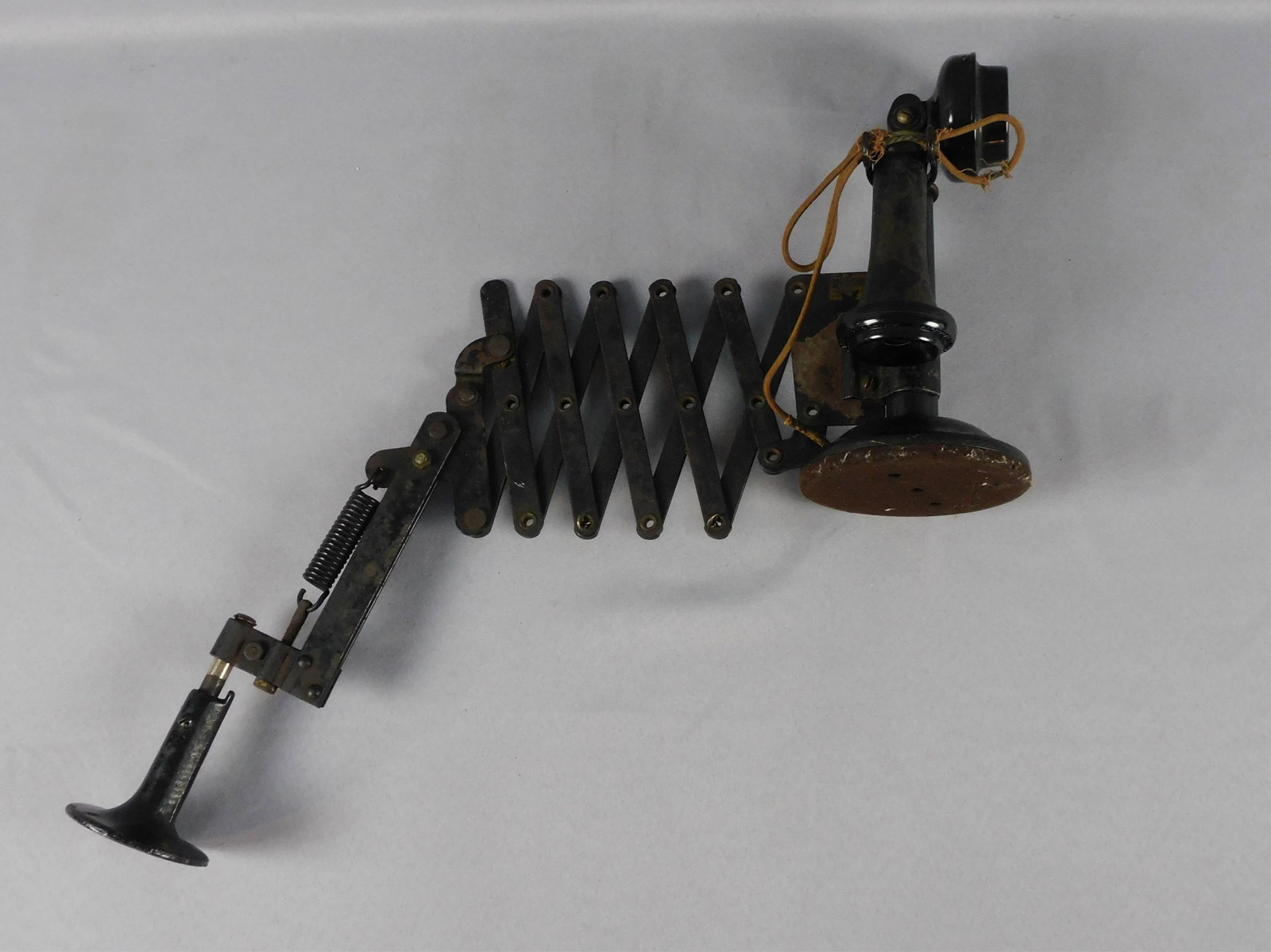 Electric scissor jack candlestick phone. Western: Electric Co, ca. 1901. Phone height is 11 1/2". 36" wide when open to 22" when closed. Black metal with painted finish. On a swivel bracket. Shows wear.