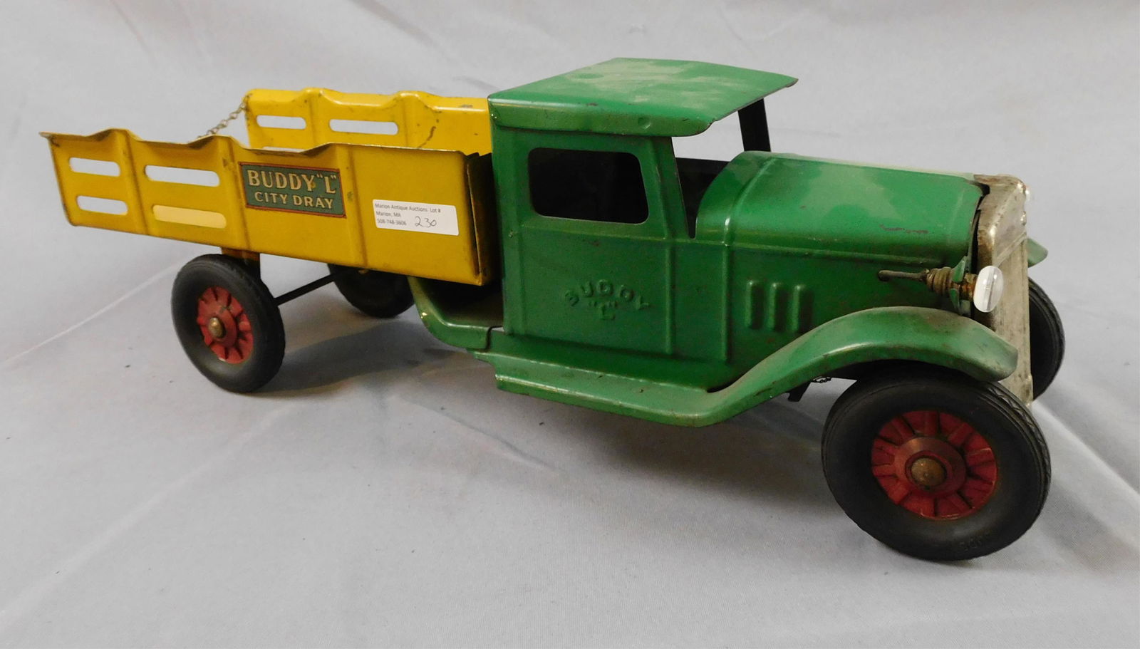 Buddy L City Dray pressed steel toy truck, ca.: 1930s. Original green and yellow paint and decals. Battery operated lights, not connected. Chrome grille, rubber wheels. 19" long, 6" wide, 6 3/4" high. Shows age appropriate wear, minor paint loss.