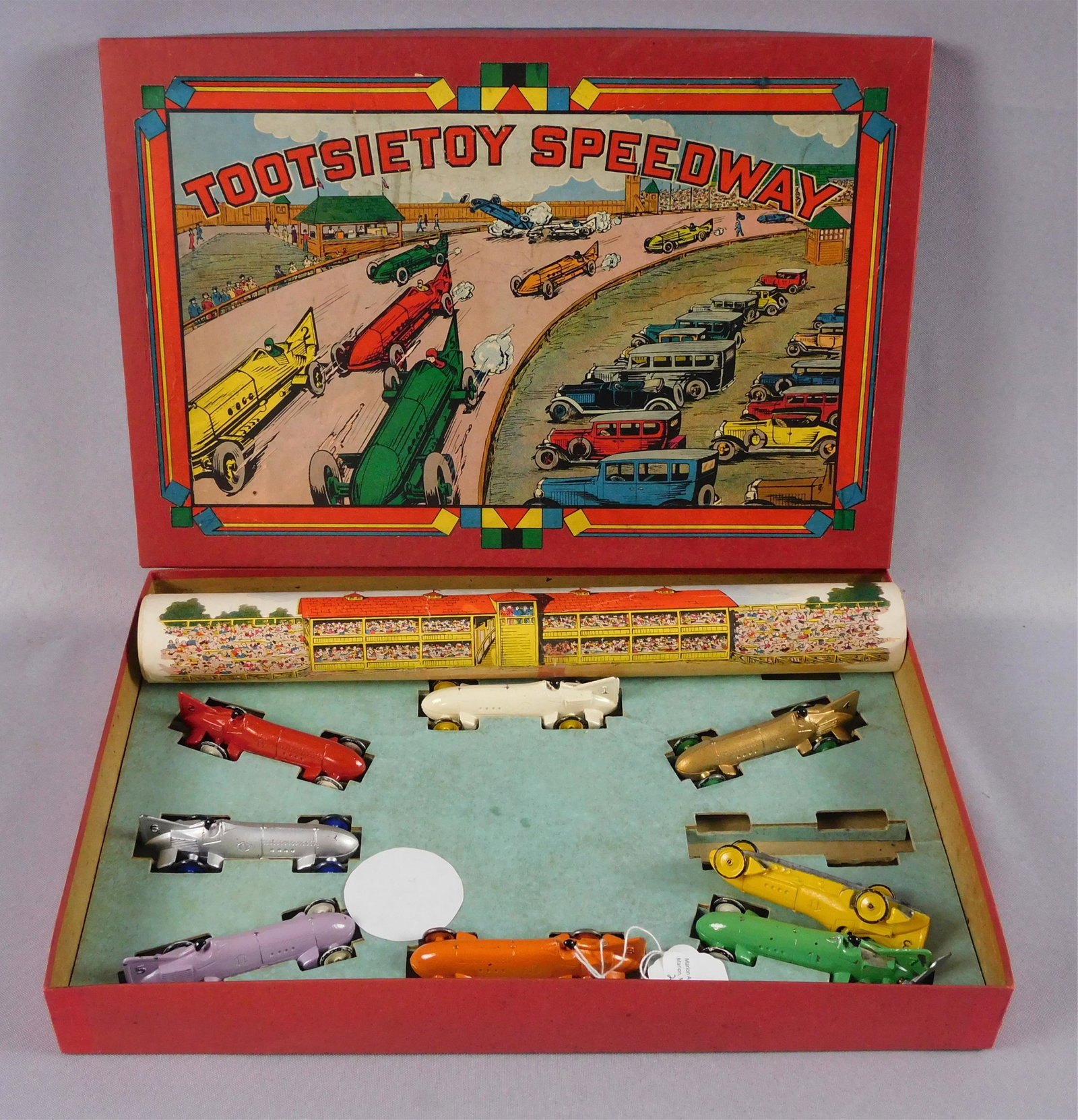 Tootsietoys Speedway game, mid 20th c. 8 steel: racing cars, 3 1/2" long. Original box with colored lithograph on cover. Comes with a roll up paper race track. Two slots in the box that are empty, so something appears to be missing. The box measure