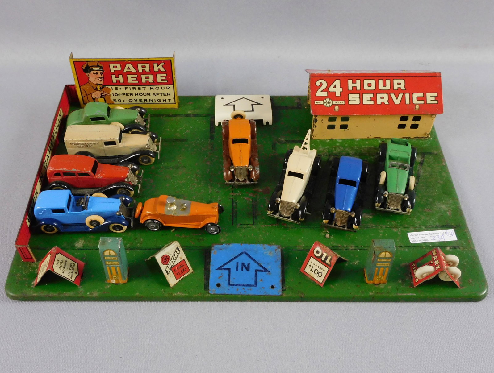 Marx pressed steel 24 Hour Service Station toy: set, ca. 1930s. Includes front pumps, missing hoses. Oil change sign, tire change display (one tire missing), a "Work Guarantee" sign, and a gasoline sign ("5 gallons for $1"). Comes with 8 vintage 19