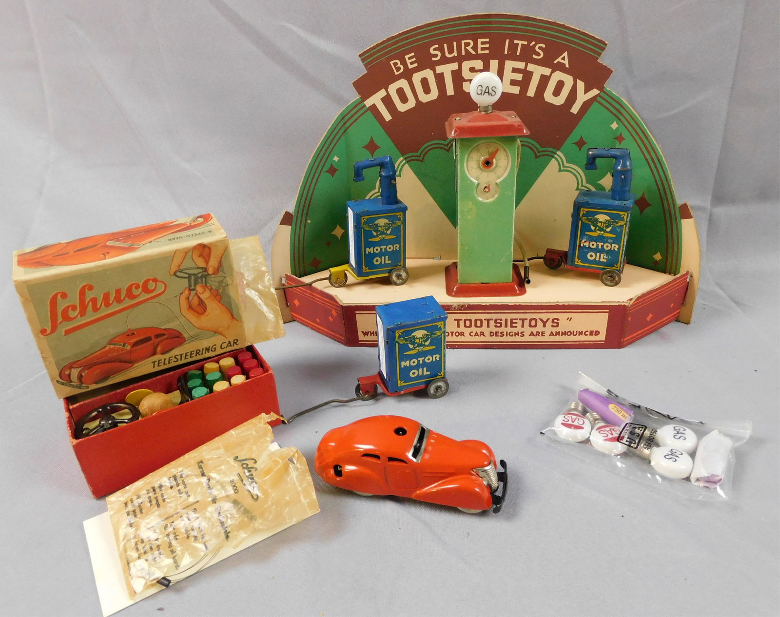 12-piece toy lot, to include: cardboard: Tootsietoy display, 9" high, 12 3/4" wide, 3" deep, excellent condition. A litho tin gas pump, battery operated, with crank, mechanized dial, electric light, 6" tall. Three Marx oil tanks on wheels, o