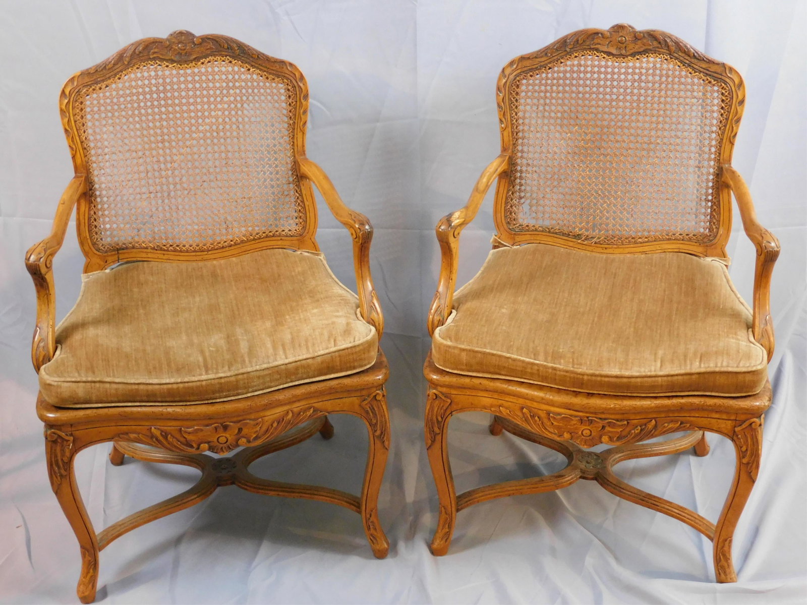 Pair of Louis XV style beechwood fauteuils. Cross: stretcher base. Cane seat is damaged and has a break to cane back. 36 1/2" high, 23 1/4" wide, 18 1/2" deep. Fitted cushions. late 18th-early 19th century.