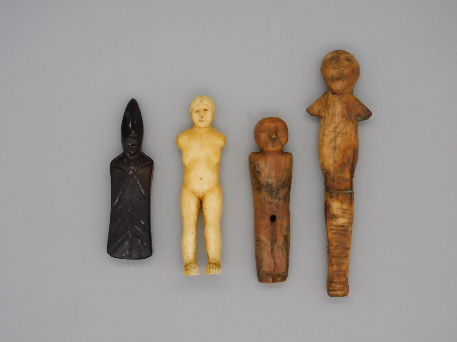 (4) Inuit carved figures. Prehistoric-19th: century. Male and female figures done with incised carvings made from walrus tusk. All figures have an old patina. 2 1/2" - 4" in height. All in age appropriate condition.
