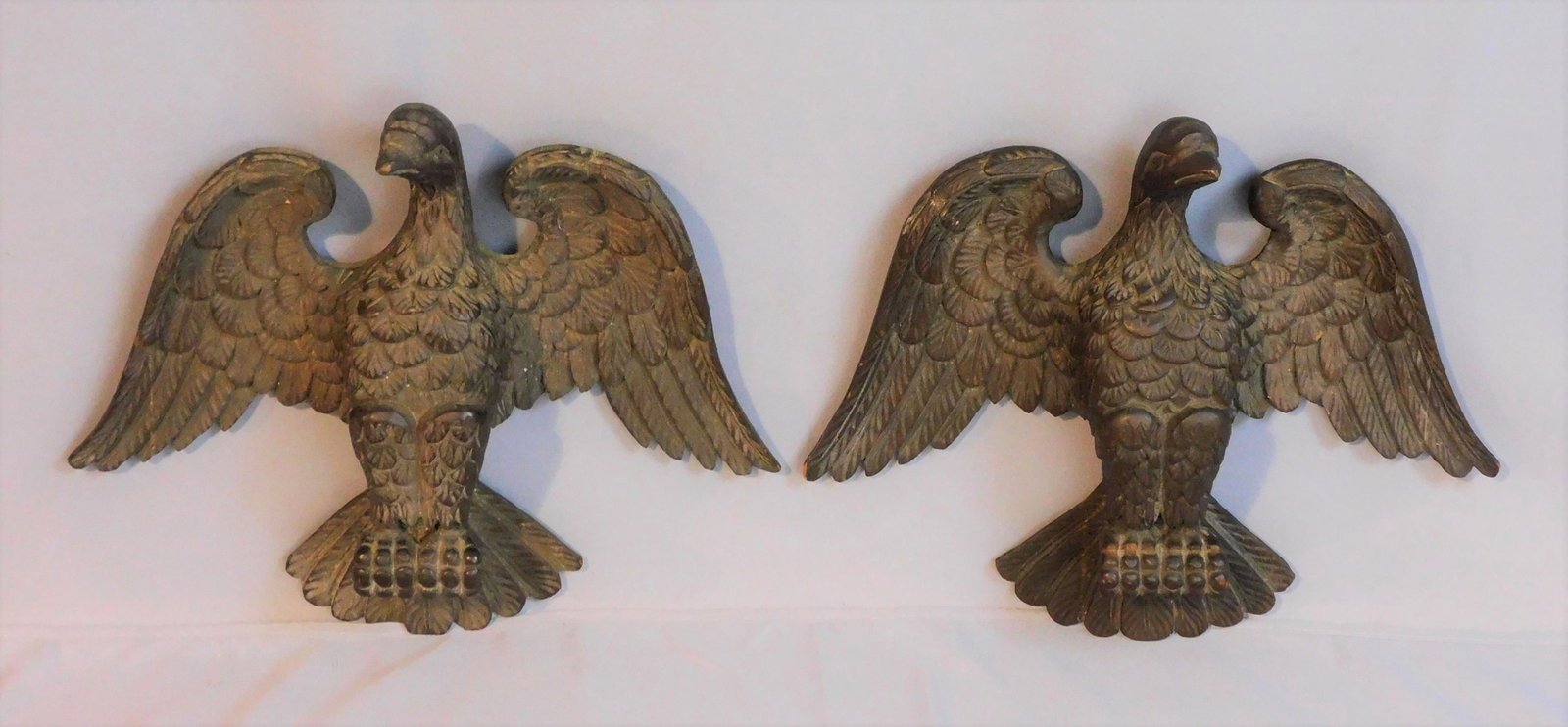 A pair of carved poplar eagles, 19th c. Two: ornately carved architectural elements depicting American eagles with wings spread. The talons form a hole. Fully carved feather decoration. 13 1/2" high, 16 1/2" wide, 4" deep. They have their origin