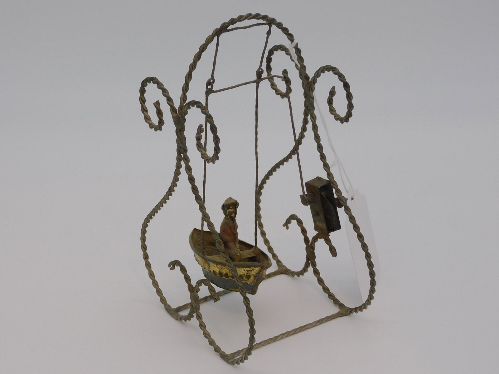 Litho tin swinging boat wind up toy, late 19th: c., with a scrolling wirework frame. Wind up spring mechanism. 7 1/2" high, 5" wide, 3 1/2" deep. Currently in working condition.