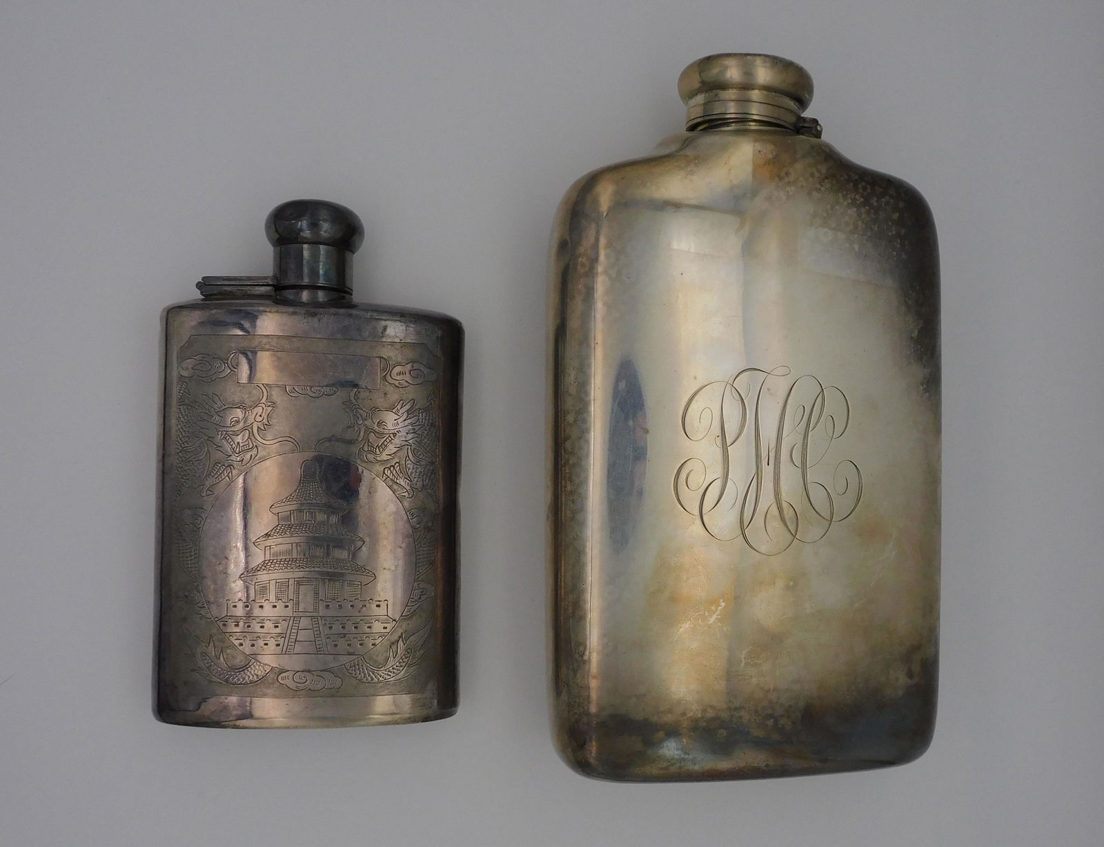 Two sterling silver flasks, to include: Tiffany: and Co., monogrammed, with minor denting. Measures 7 3/4" high, 4 1/2" wide, 1 3/4" deep. Along with a flask by Jadegreen with engraved pagoda scene surrounded by two dragons. Measures 5 3/4" high, 3
