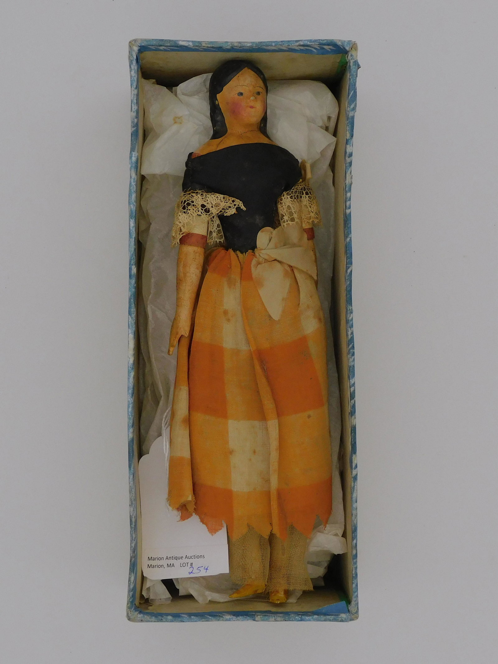 Young girl doll with a carved and painted wooden: body. Mid-19th c. Period clothing, all original in overall good condition. Skirt shows some staining. Original 19th c. box. Doll is 9 1/2" x 3", box is 4" x 10" x 4".