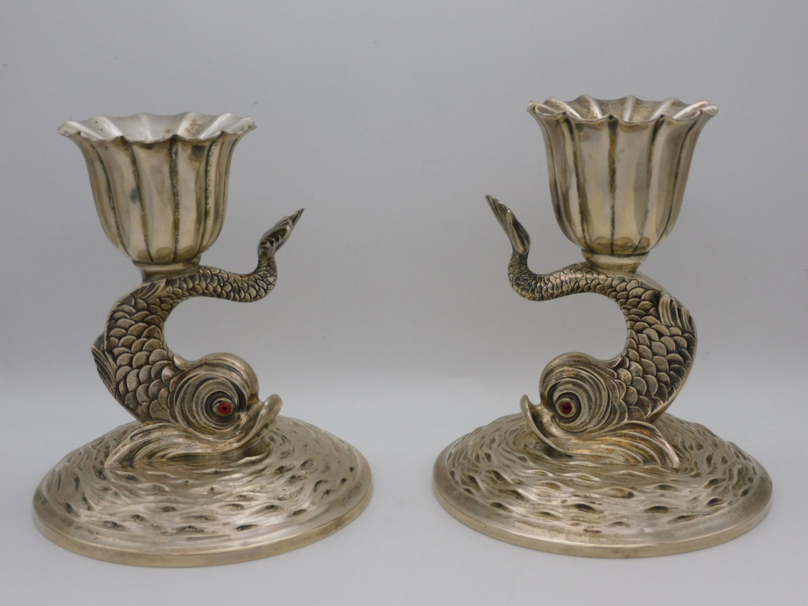 Pair of stylized sterling silver dolphin form: candlesticks with rippled water base. Glass eyes, by Timothy Tuttle, Boston. 5 1/2" high, 5" diameter at base. 22.7 total ozt.
