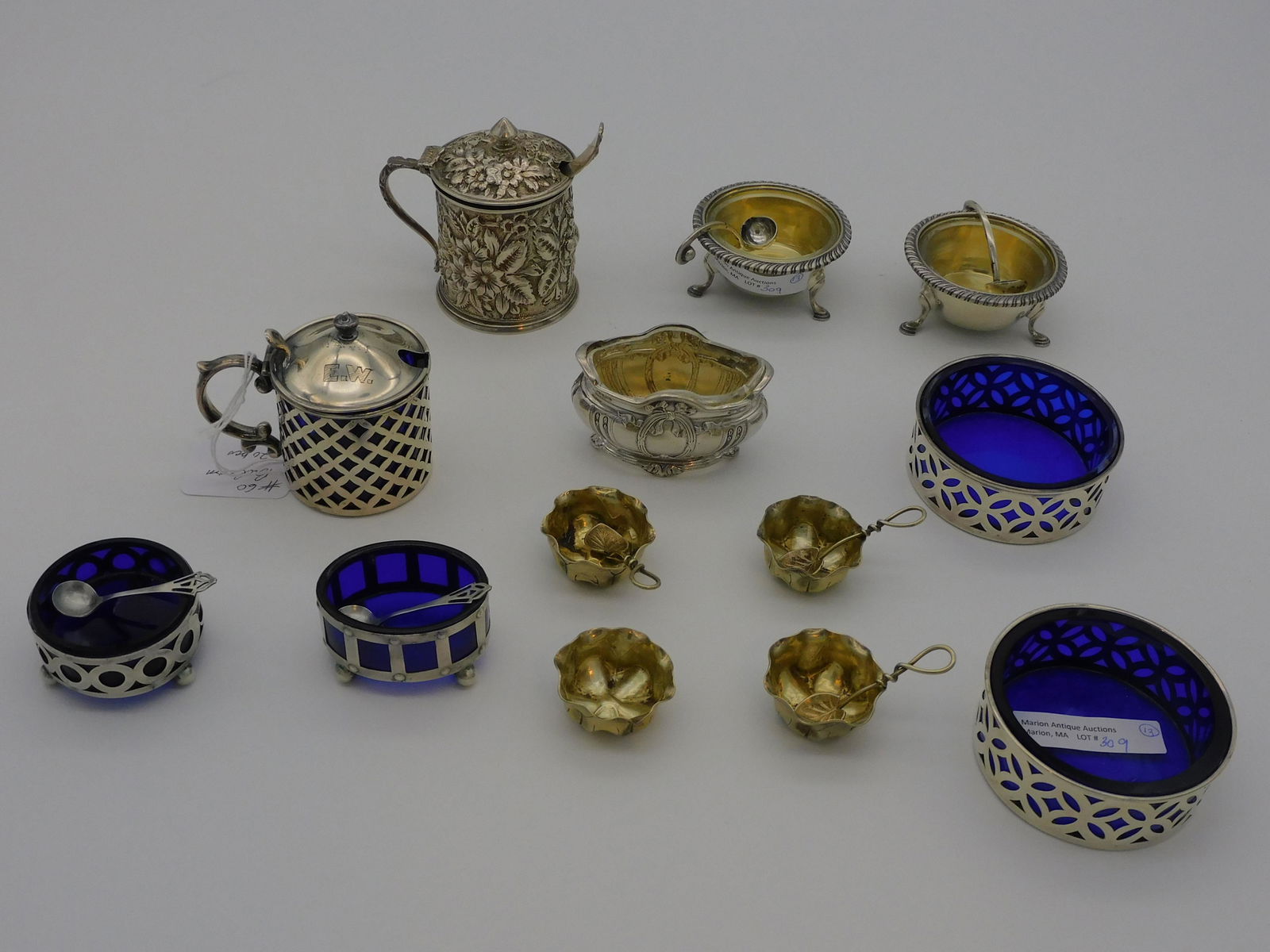 (13) sterling silver salt cellars and mustard: jars. To include: four leaf form salts by Alvin, 3/4" high, 1 3/4" wide, with 4 leaf form spoons. Two cobalt lined openwork sterling salts, 1" high, 2 3/4" diameter. Two Redlich sterling open salts wi