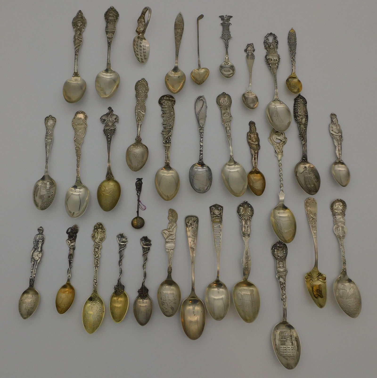 (33) sterling silver souvenir spoons, to include:: two spoons with the figure of a Native American man, one with an engraved bowl that depicts a volcano "Pocatello ''. Others depicting Washington D. C., Indianapolis, Massachusetts, Lexington (Kentucky