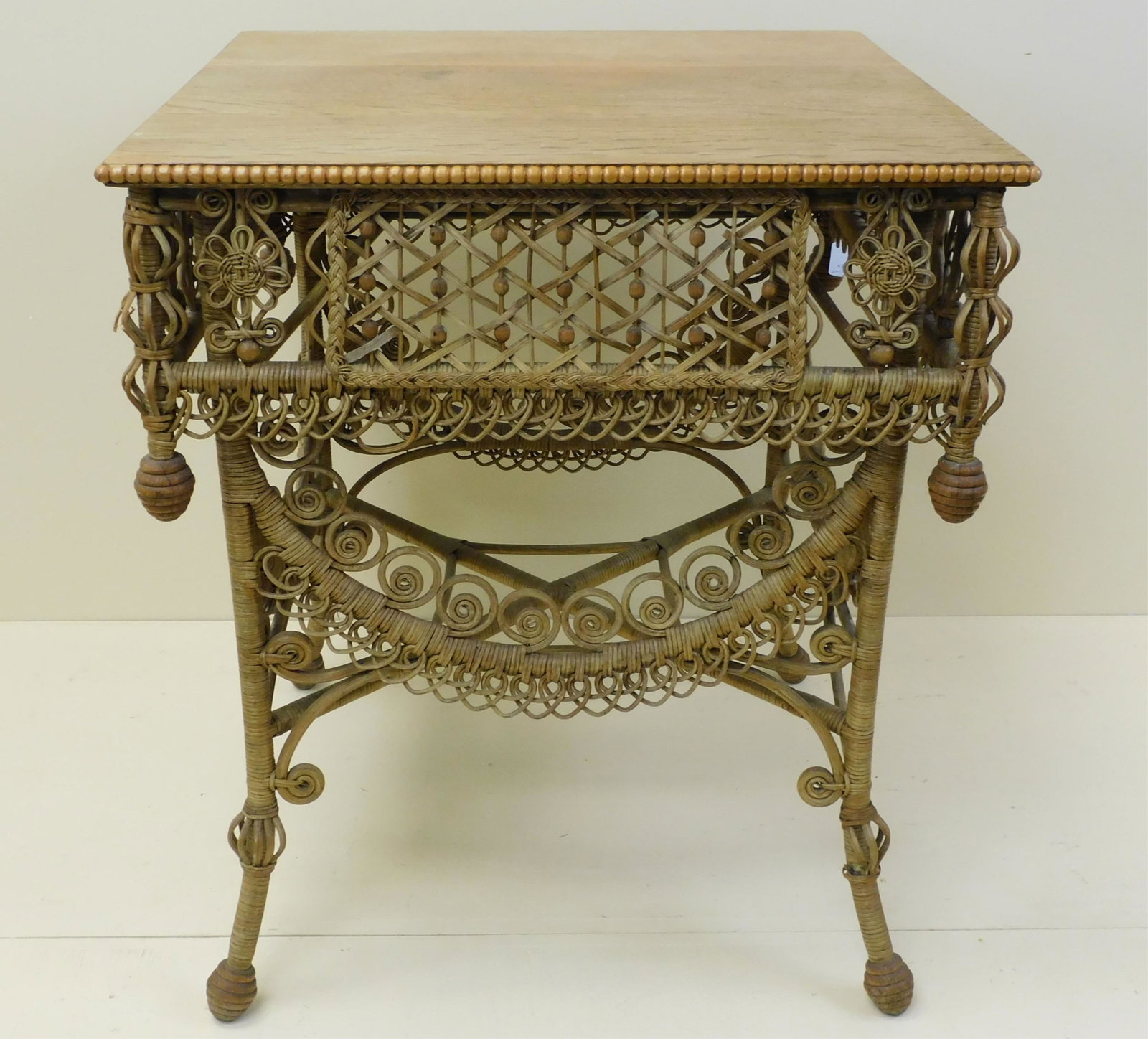 Ebullient wicker parlor table, 1890. Unknown: maker, highly detailed. Square quarter sawn oak top with beaded trim and bead and scrollwork skirt. Turned wood finials. 30" high, 26 1/2" x 26 1/2". Natural finish. Provenance: Mary Jean McLaughlin C