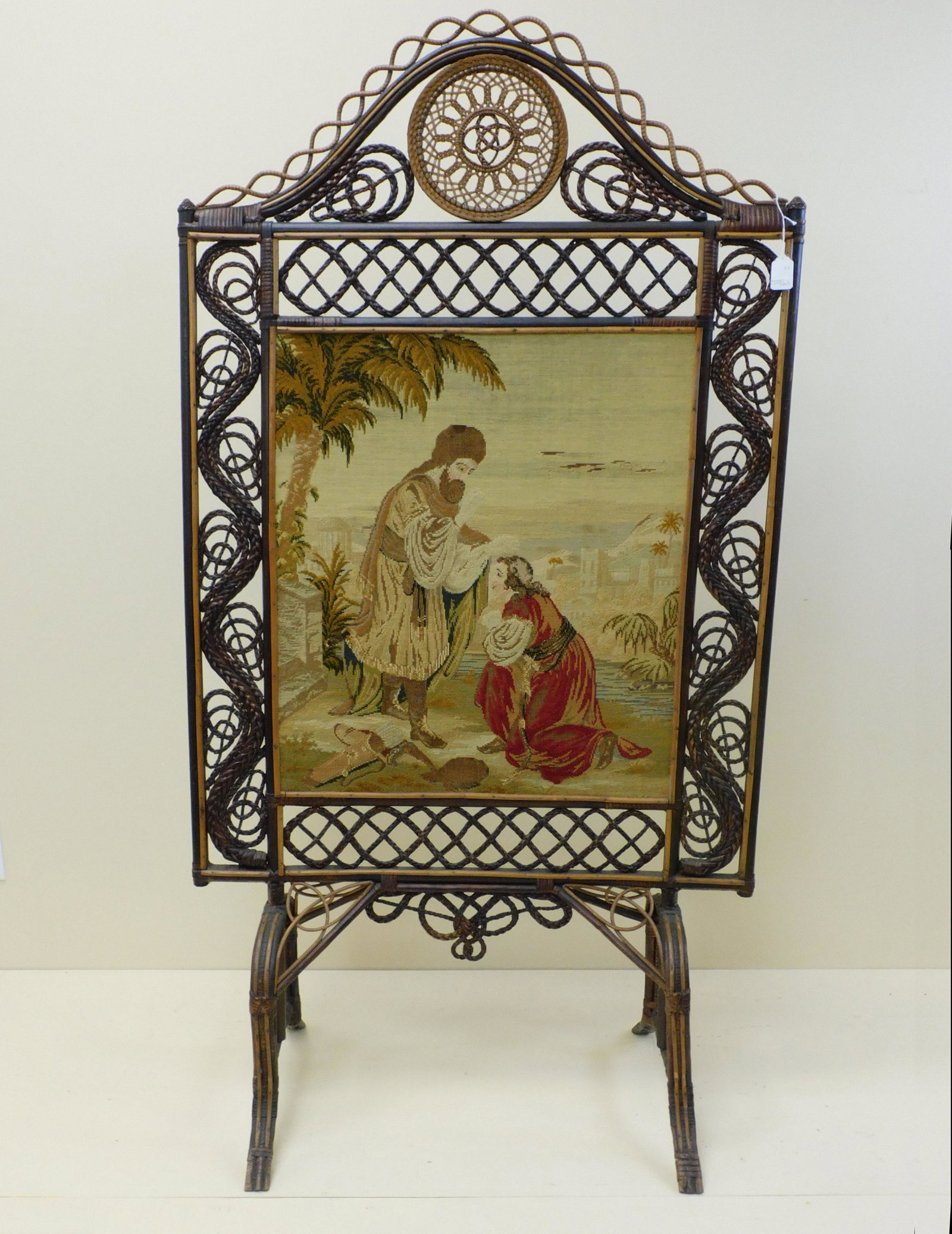 Rare Victorian wicker fire screen, ca. 1875.: Rattan and wood with an inset cloth tapestry featuring a Biblical scene. Unusual rope twisted borders, trestle style base. 62 1/2" high, 33 1/2" wide, 18" deep. Old finish, possibly original. Overall 
