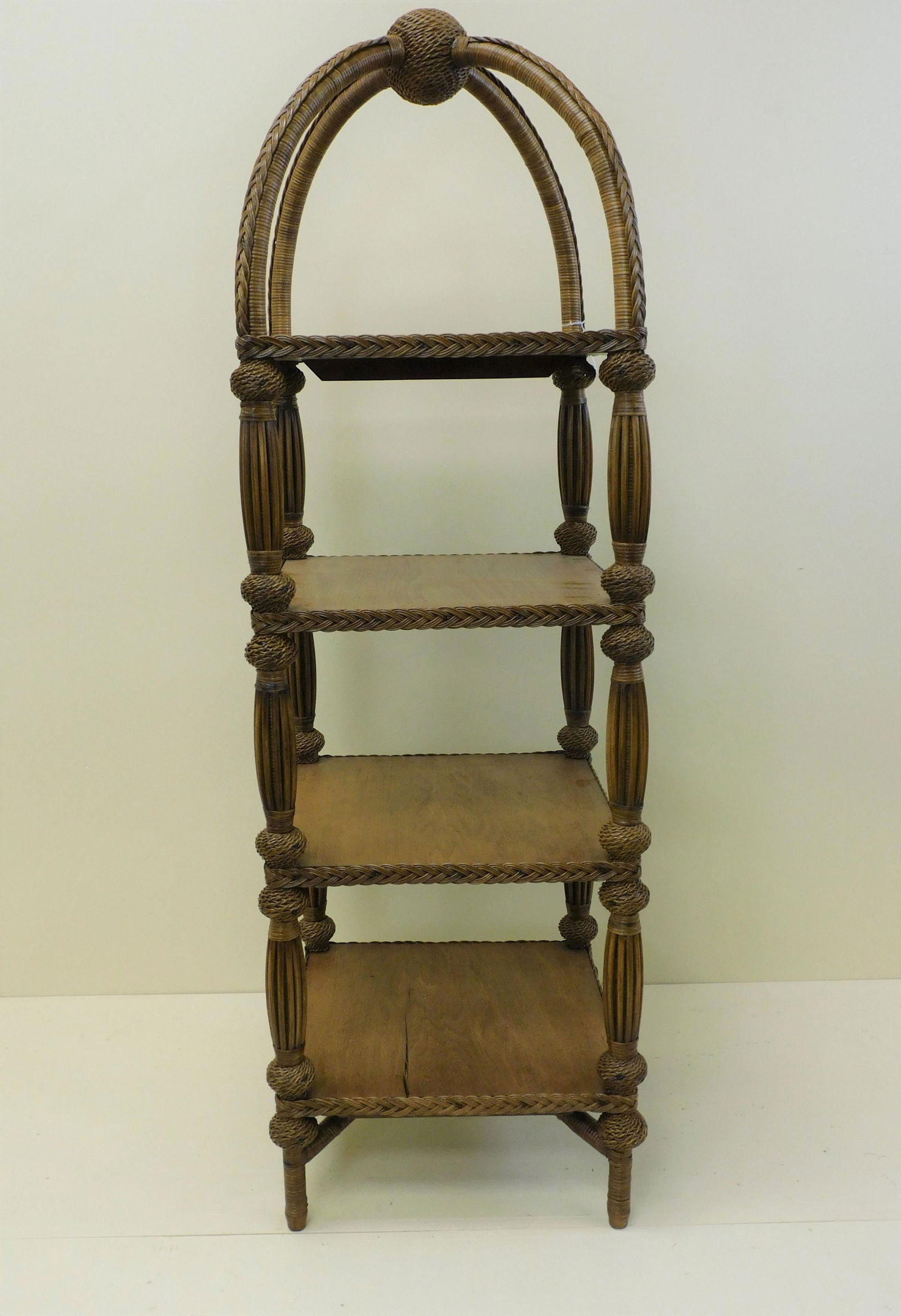 A fine and rare four tiered wicker etagere, ca.: 1898. Possibly made by Heywood Brothers Wakefield Co. Unusual woven ball design at the top with birdcage trim on the sides. 60" high, 18" wide, 18" deep. Old refinished natural surface. Bottom shelf s