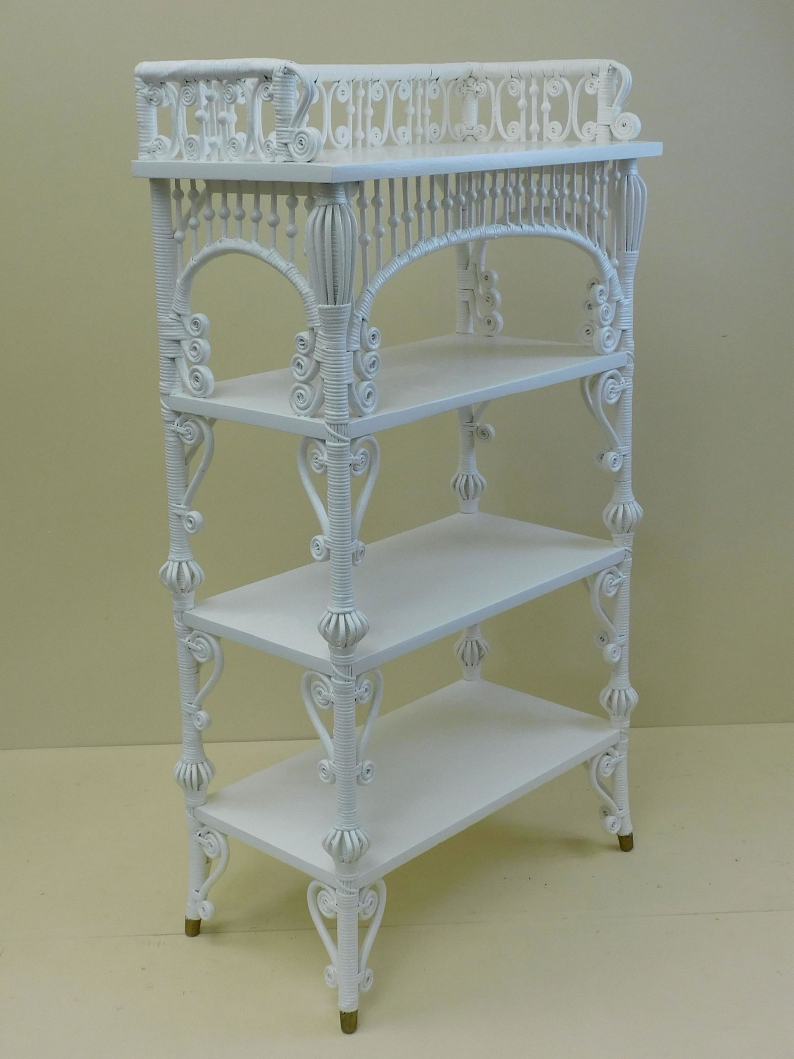Victorian wicker etagere, ca. 1890. Wakefield: Rattan Co. original label on underside of bottom shelf. Modern white paint with ornate gallery, four solid oak shelves, and a birdcage design on the frame. 46" high, 26" wide, 13" deep. Excellent cond