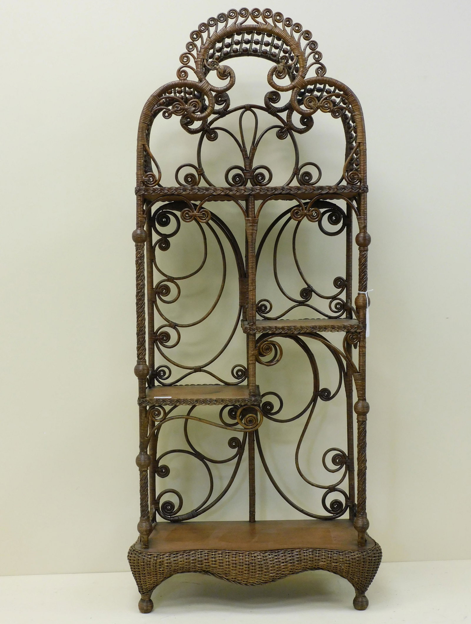 Fancy Victorian wicker etagere, ca. 1890, rattan: with oak shelves. Unusual dome shaped gallery at top. Three central shelves, serpentine shelf at base with rolled edge. Natural finish. 61" high, 23 1/2" wide, 11" deep. Overall good condition, shows 