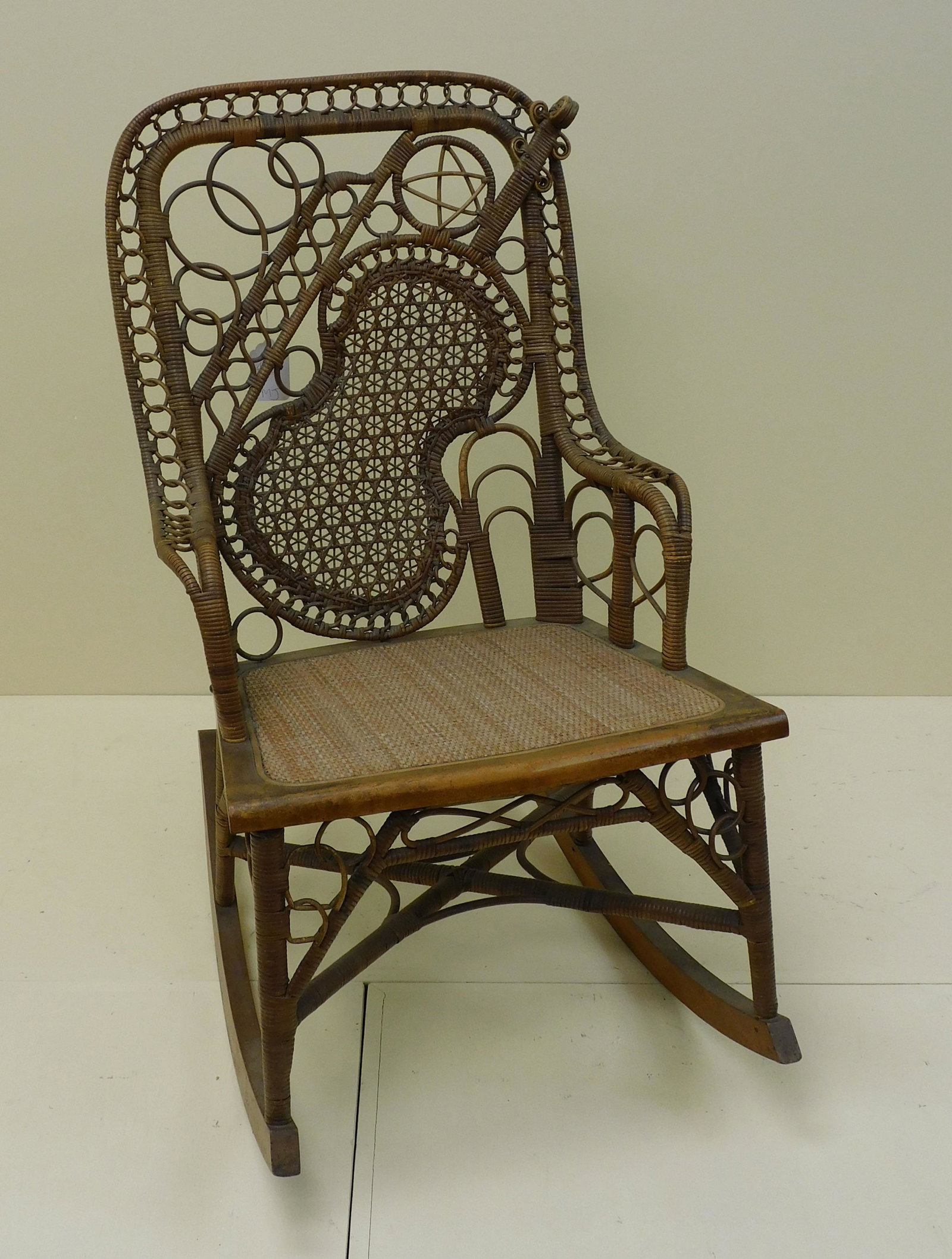 Victorian wicker theme back rocker, probably: Wakefield Rattan Co., ca. 1876. Original natural finish, violin themed back. Rattan with oak frame. 35" high, 19 3/4" wide, 17" seat depth, 29" overall depth. In remarkable original condition. It has 