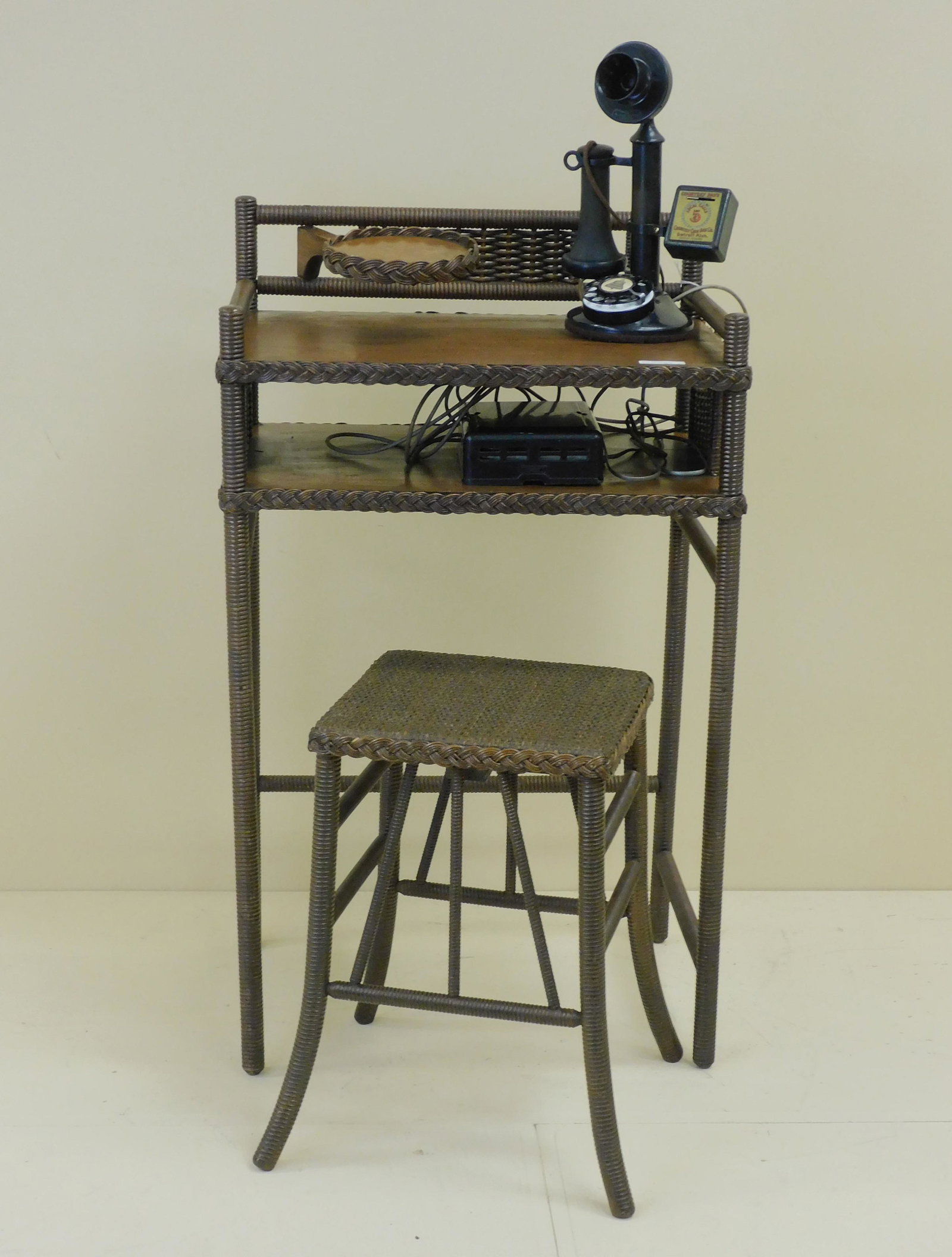 Antique wicker telephone table and stool, Heywood: Wakefield Co., ca. 1915. Rattan with oak shelves and frame. Features a swivel stand to hold the telephone and a lower compartment for phone books and papers. There is also a matching stool. Original n
