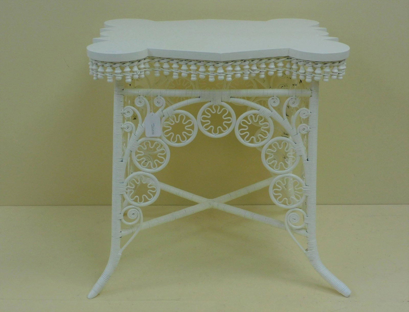 Victorian wicker table, ca. 1885. Unusual shaped: top with turret corners. Beaded skirt, elaborate pinwheel design on legs. 29 1/2" high, 28" wide, 22" deep. Modern white painted finish. Excellent condition. Provenance: Mary Jean McLaughlin Collectio