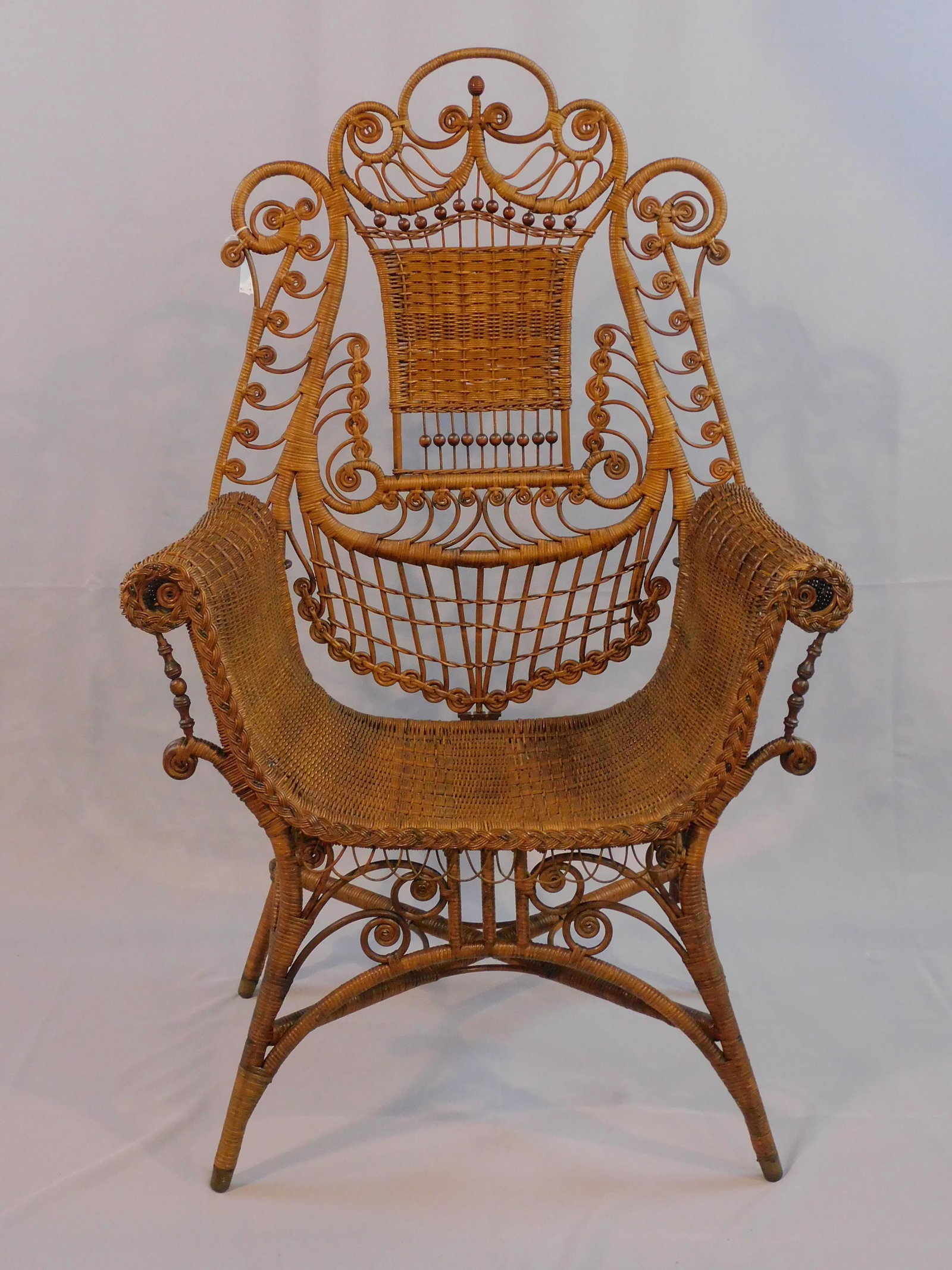 Victorian wicker reception chair, ca. 1890.: Original natural finish, elaborate back rest with ball and curlicue design. Back piece can be removed to become a Turkish bench. 48" high, 30" wide, 18" deep. Very good condition with several minor ar