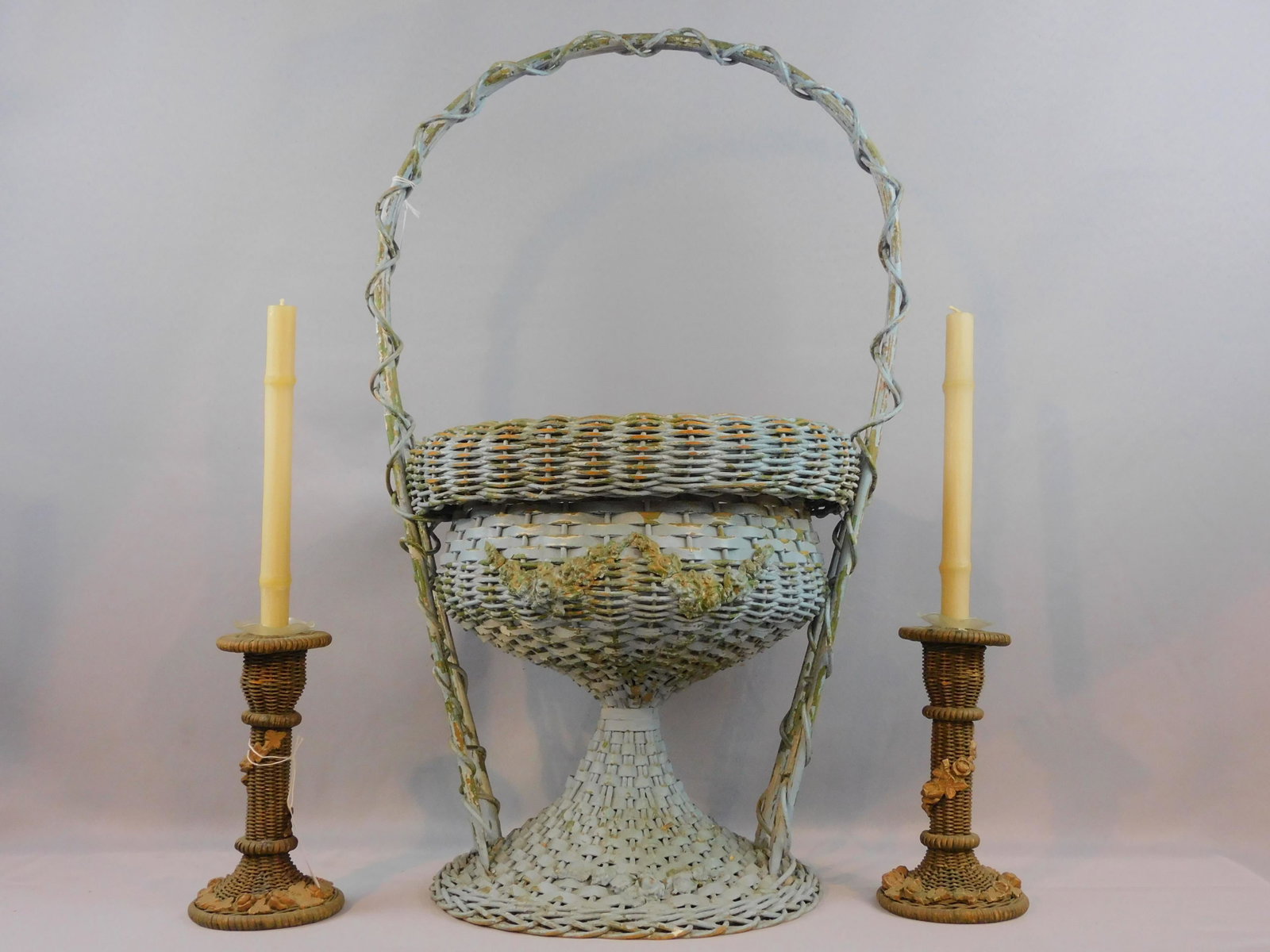 (4) antique wicker pieces, ca. 1920, to include:: rare pair of candlesticks in original paint with applied floral gesso design, 9" x 5", good condition, one slightly leaning to one side. Footed wastebasket with applied floral and swag design in old w
