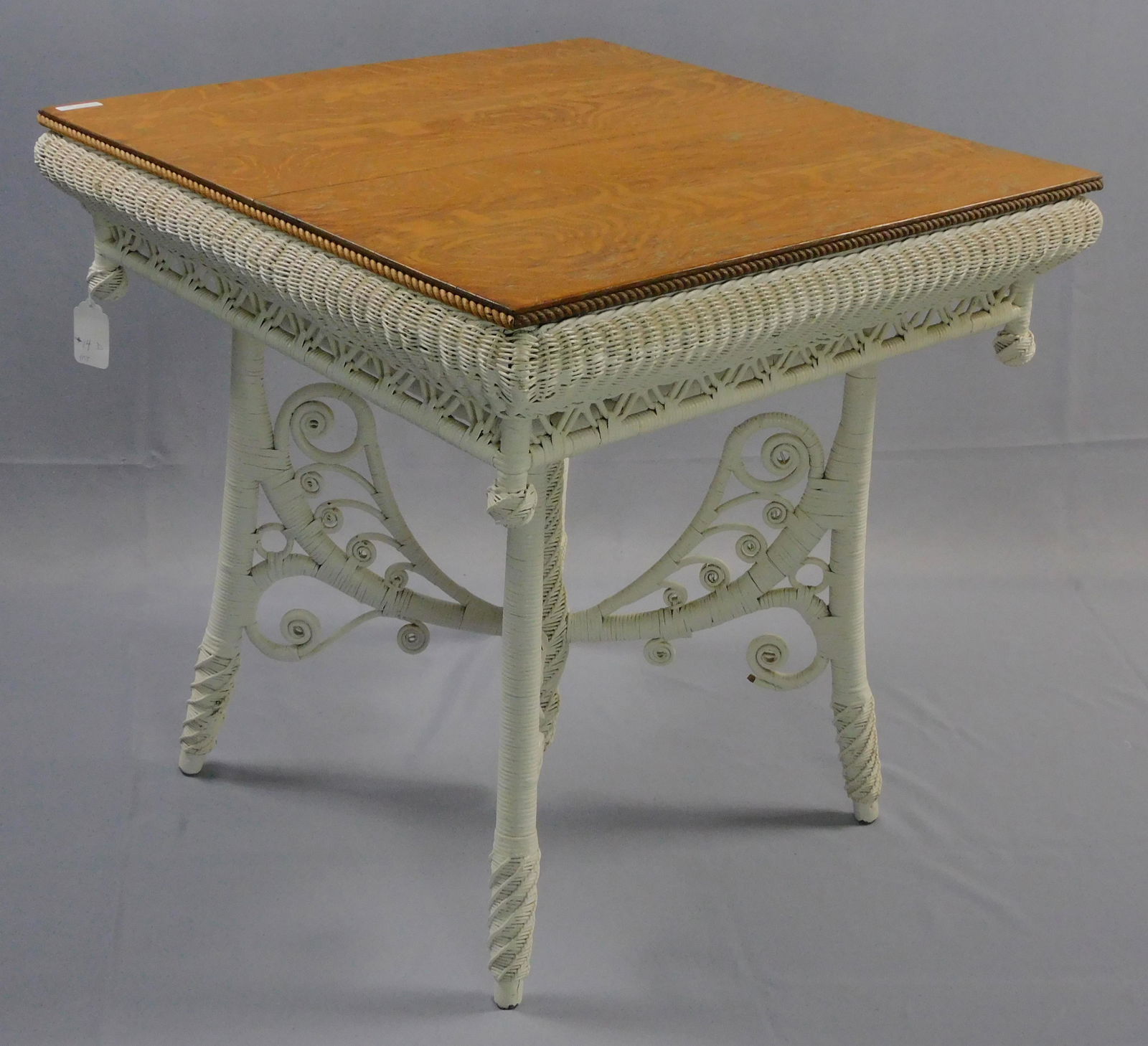 Victorian wicker lamp table, ca. 1898. Heywood: Brothers Wakefield Co., no. 6415 in the 1898 catalog. Quartersawn oak top with rolled edges, elaborate curlicue and spiral turned base. Modern white paint, top has been refinished. 28" high, 28" x 28"