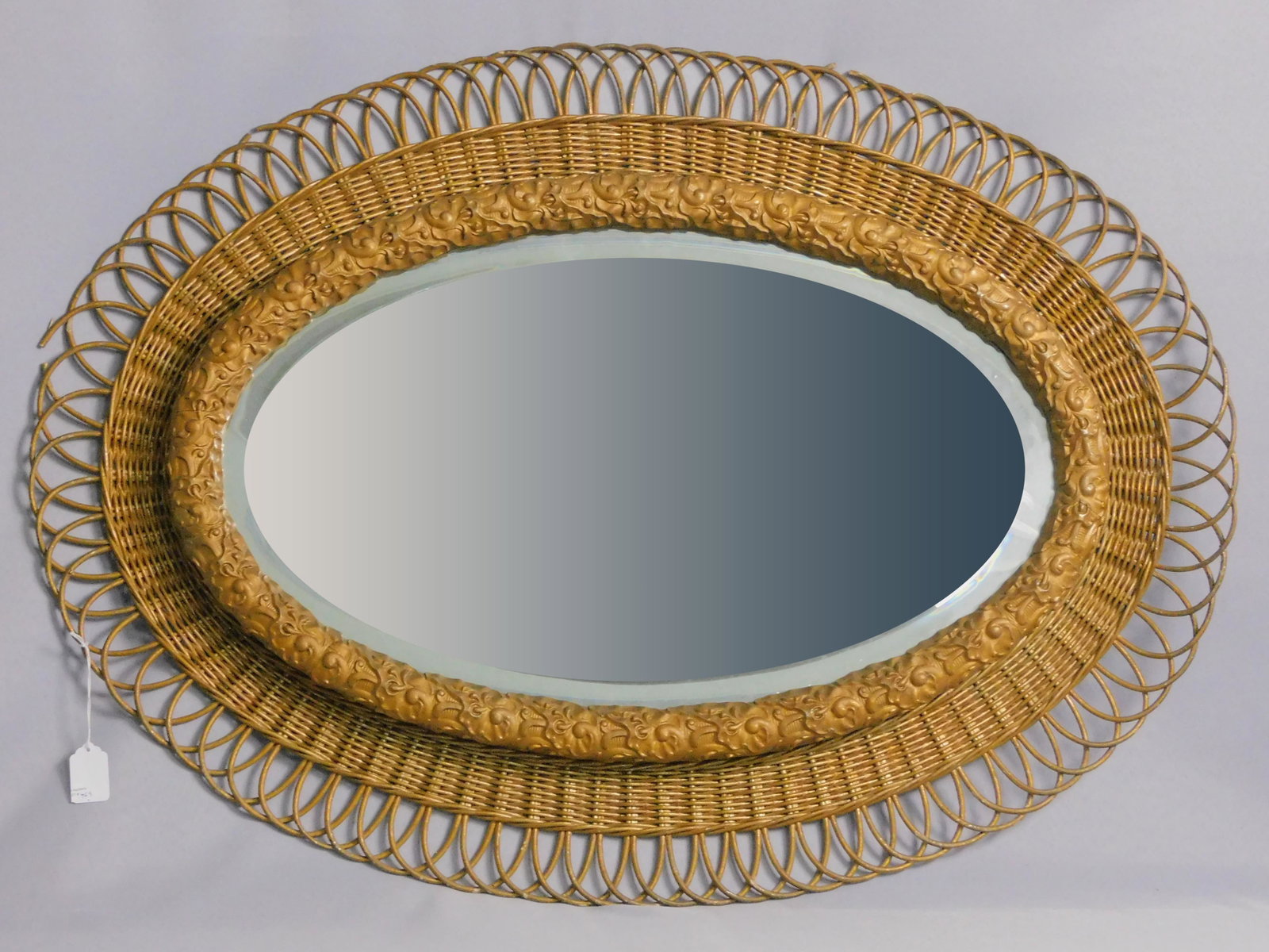 Rare oval wicker mirror, ca. 1900. Beveled mirror: with embossed gesso inner frame. 35" x 25". Old gold painted finish. Shows 3 small breaks. Open loop trim. Provenance: Mary Jean McLaughlin Collection.