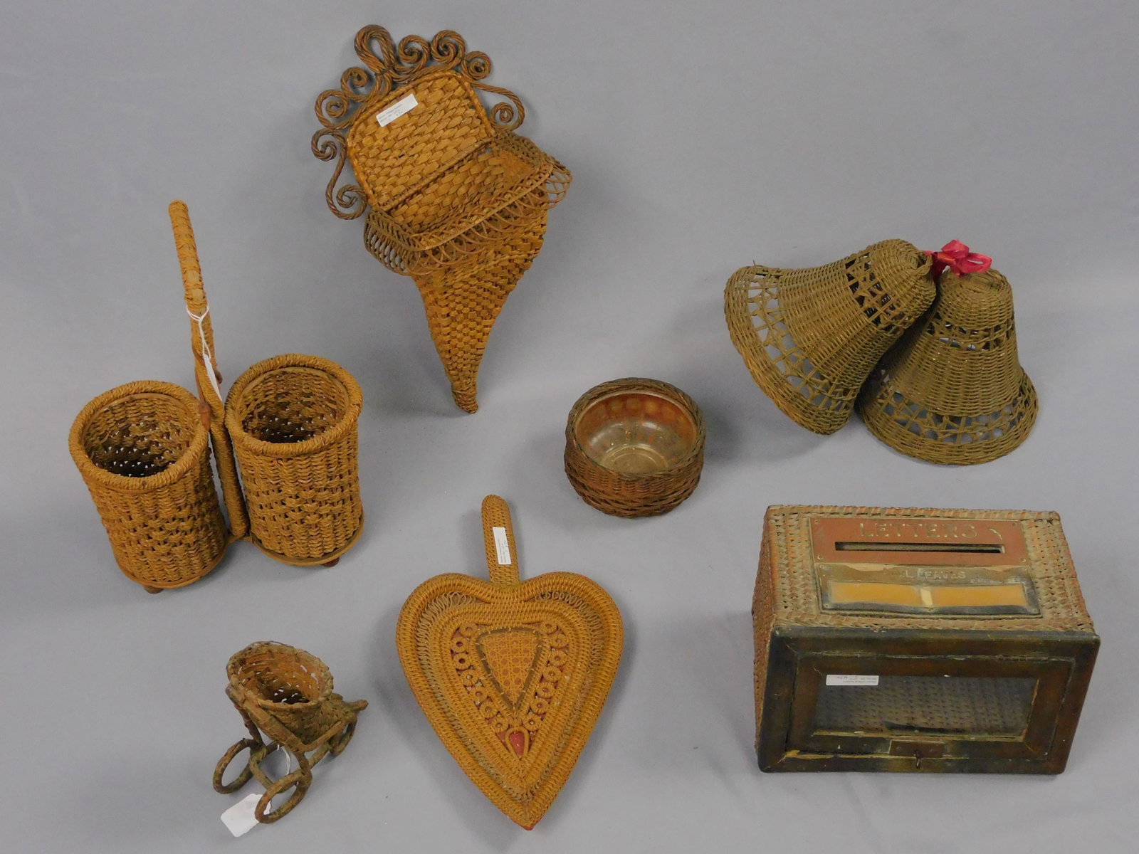 (7) piece vintage basket lot. To include: rare: wicker mailbox, original finish with locking door, brass front, 7" high, 10 1/2" wide, 6" deep. Bottle holder, original finish, 16" high, 10" wide. Palm shaped tray, 8 1/2" wide, 15 1/4" long. Cornuco