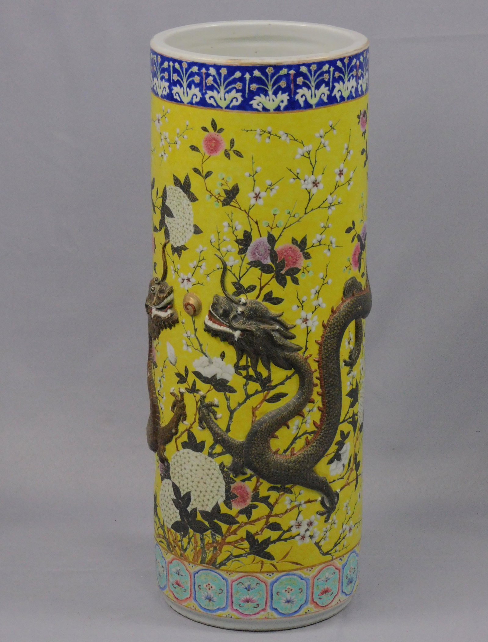 Chinese stoneware umbrella stand, late 19th c.: Yellow field with floral design and raised dragons. Overall good original condition, very faint spider crack lines in base. 26" high, 9 1/2" diameter.